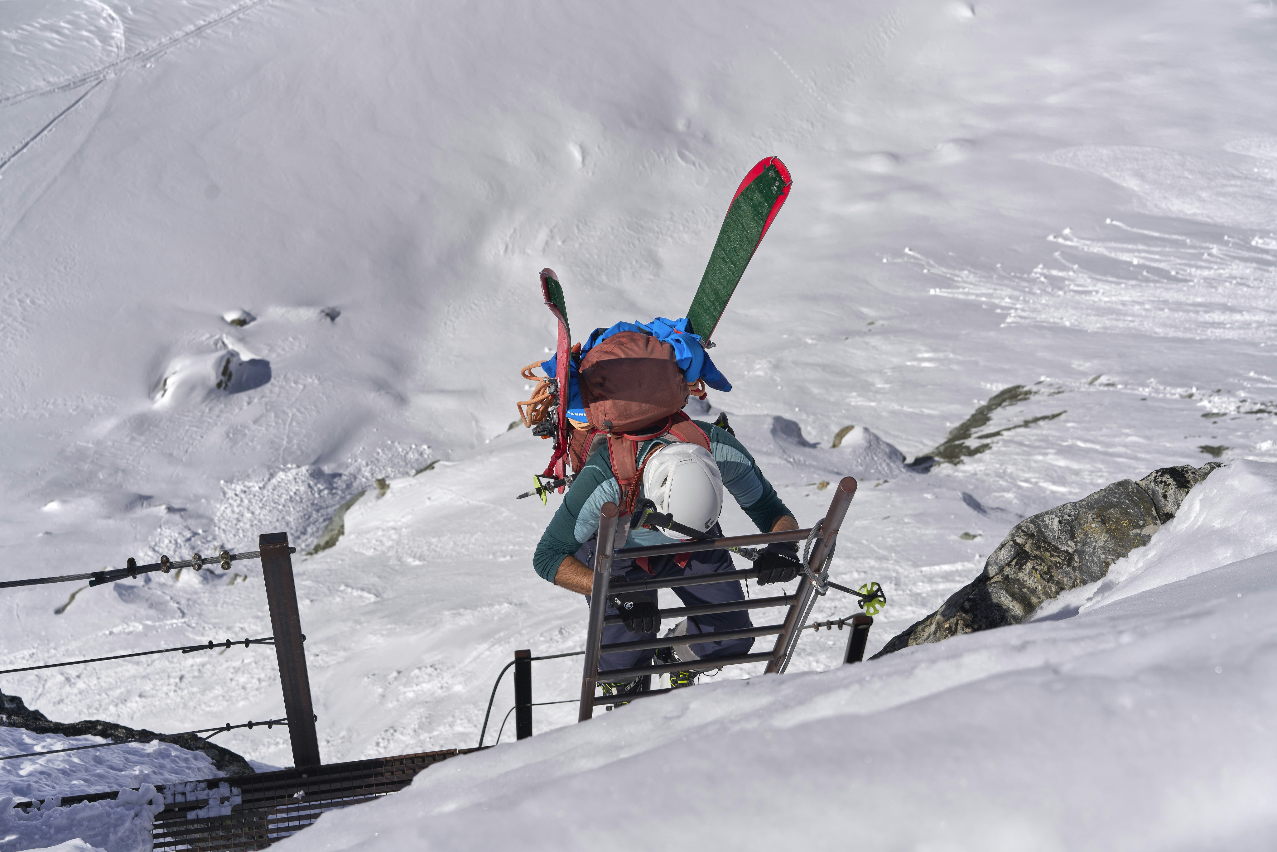 Skifahrer, der eine Leiter in verschneiten Bergen erklimmt