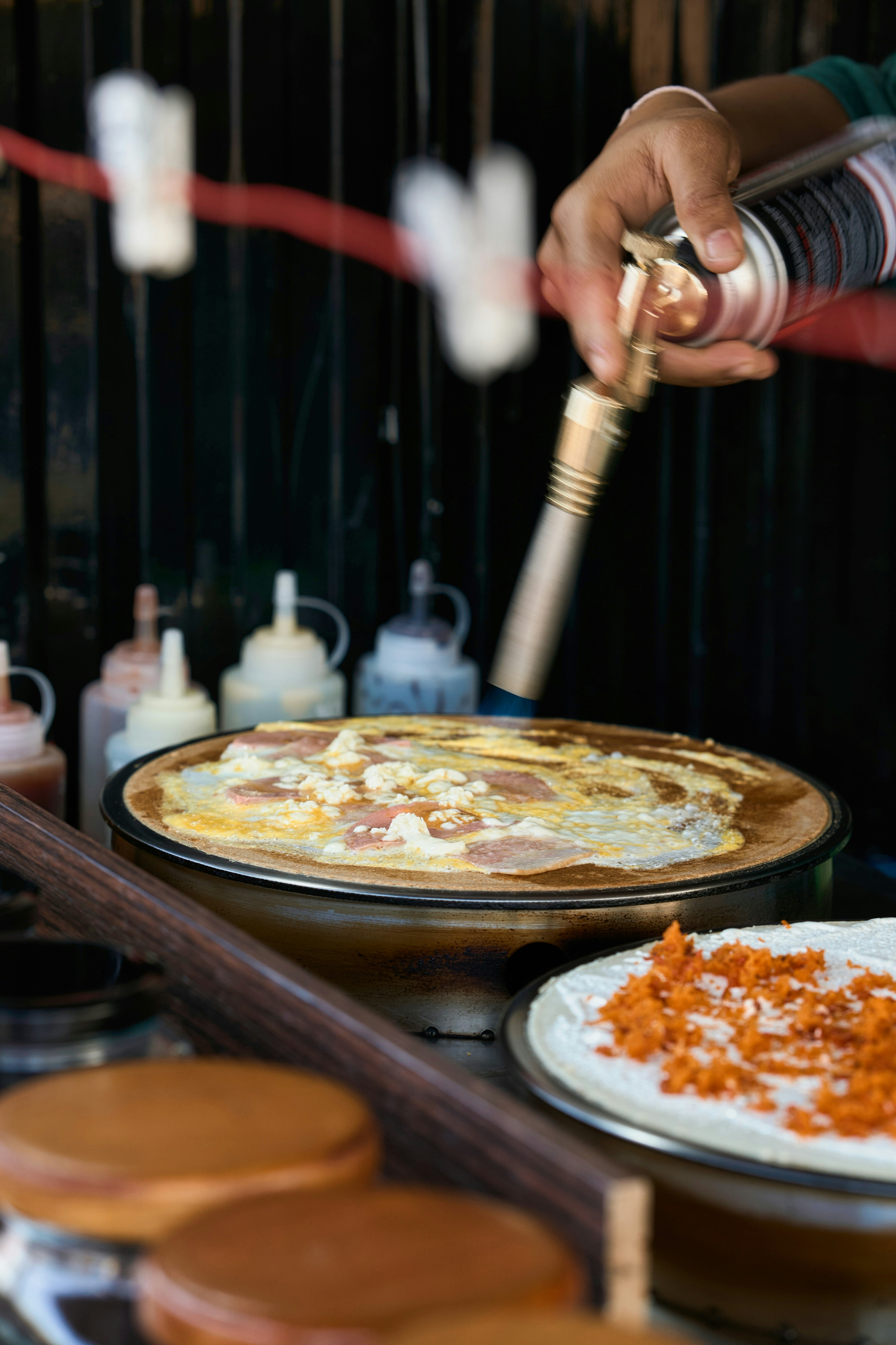Eine Person karamellisiert eine Crêpe mit einem Brenner.