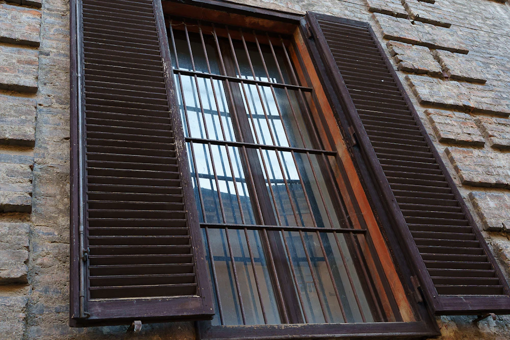 Window with wooden shutters and metal bars