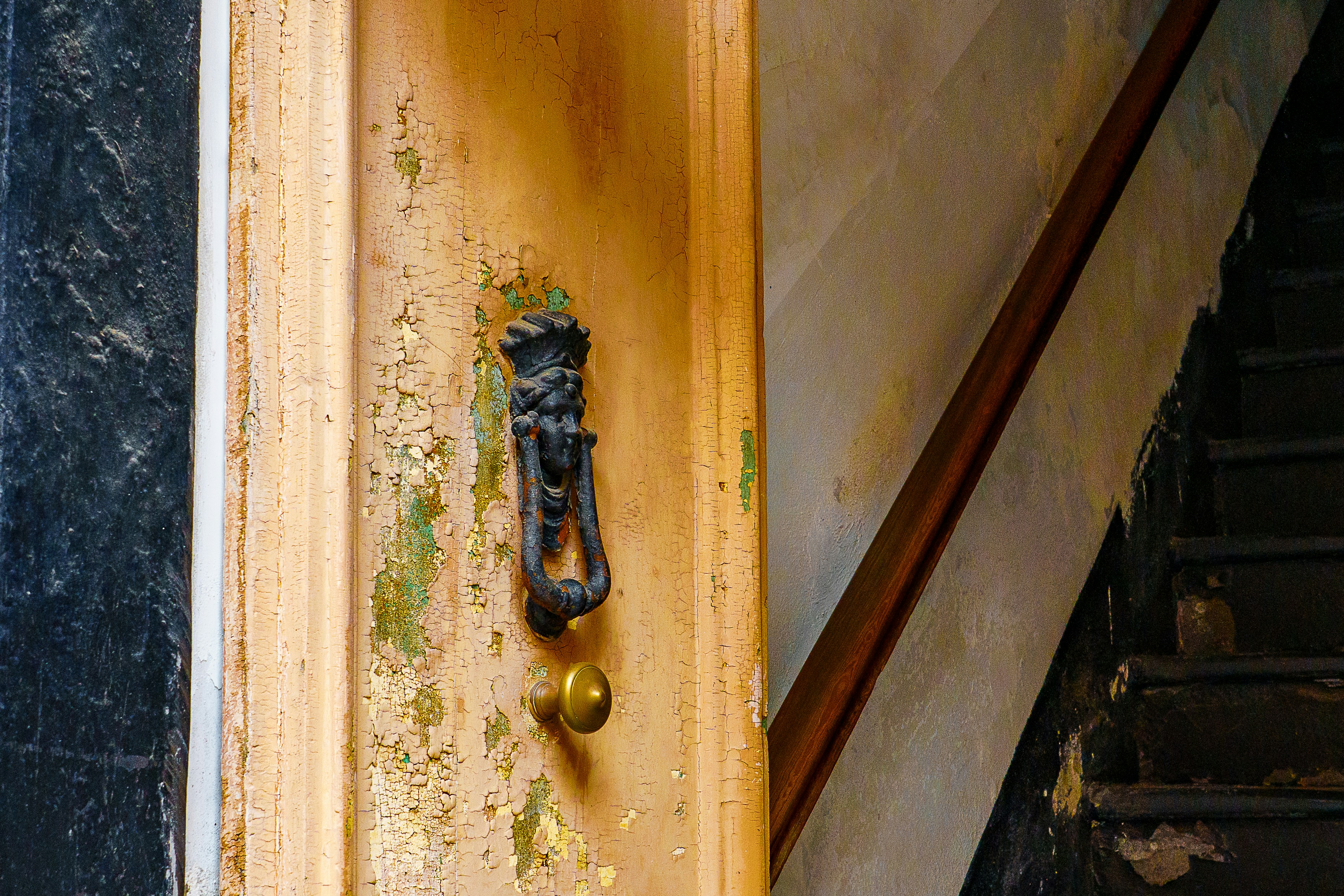 Old wooden door with ornate knocker and brass knob.