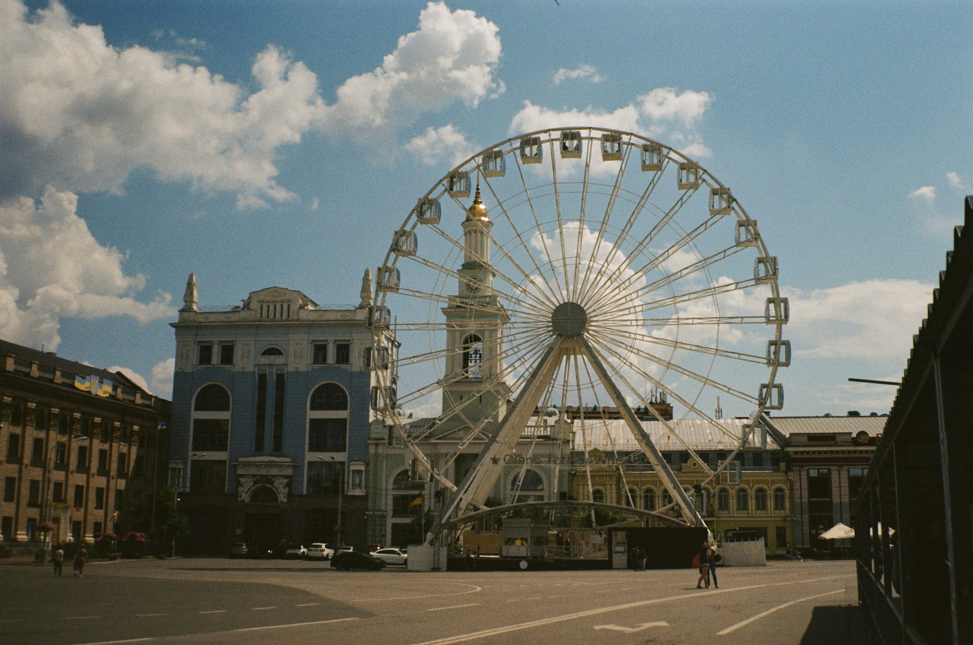 Ferris wheel in a city square with buildings.