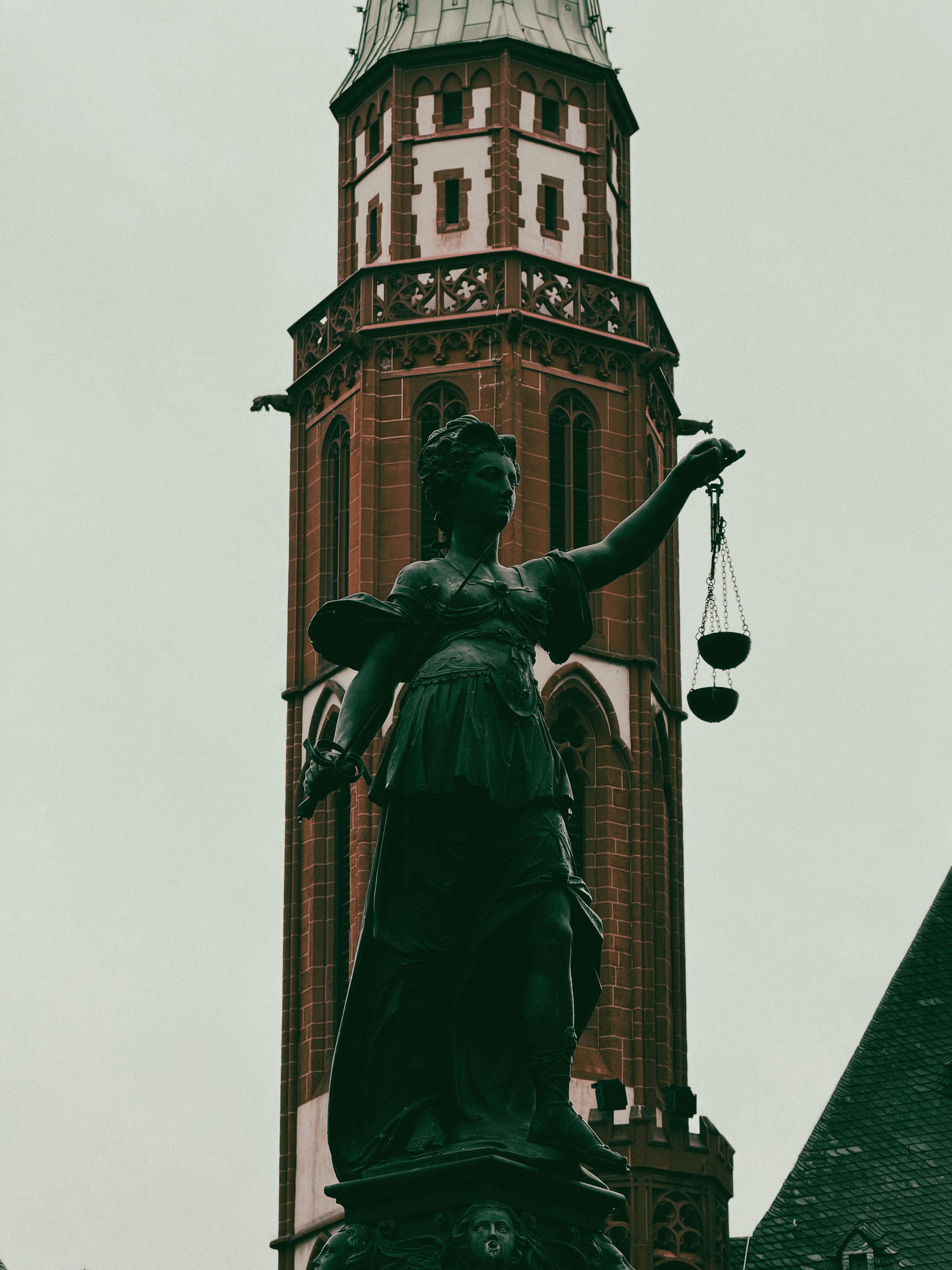Estatua de la justicia frente a una alta torre
