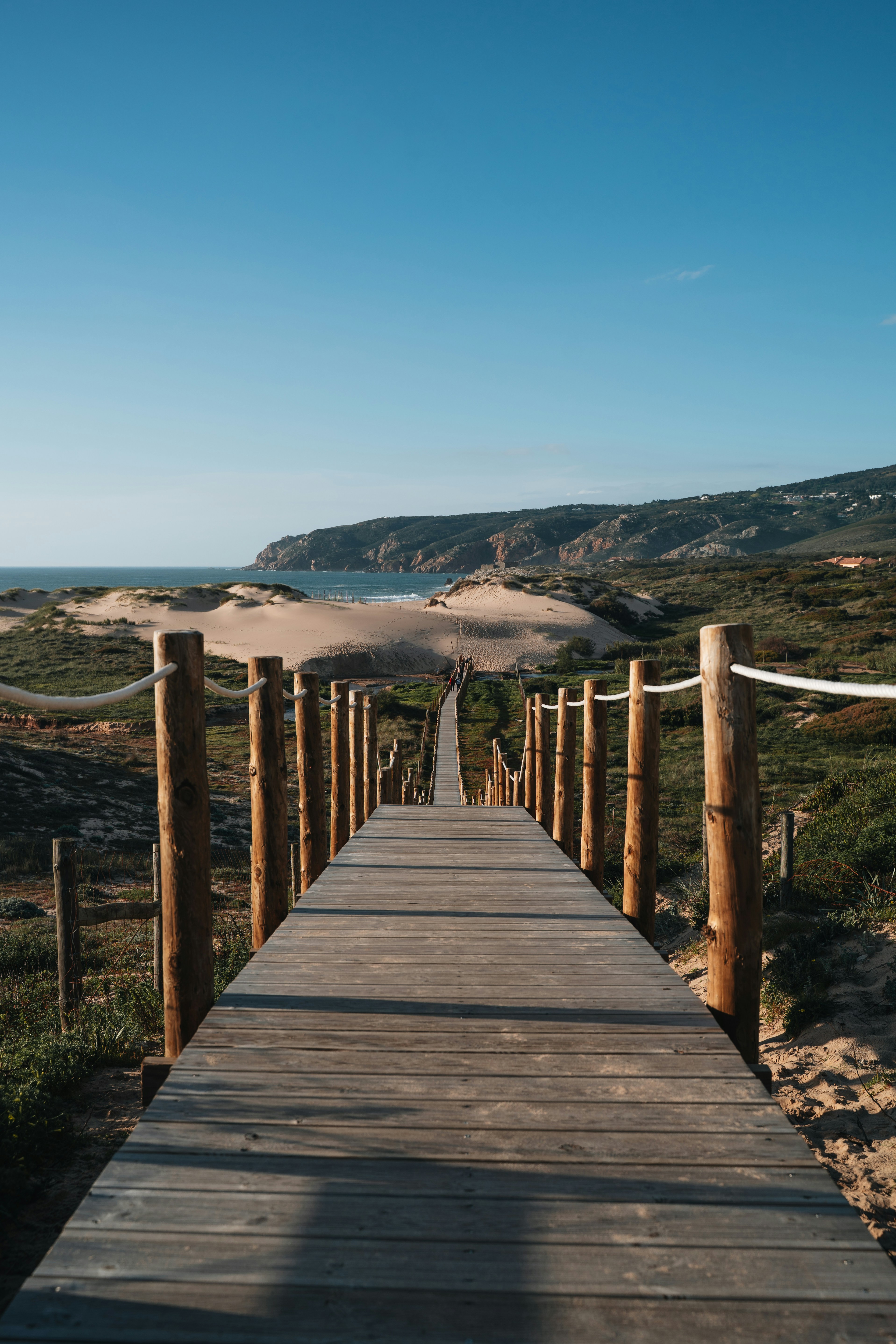 Wooden walkway leading to a sandy beach and ocean.
