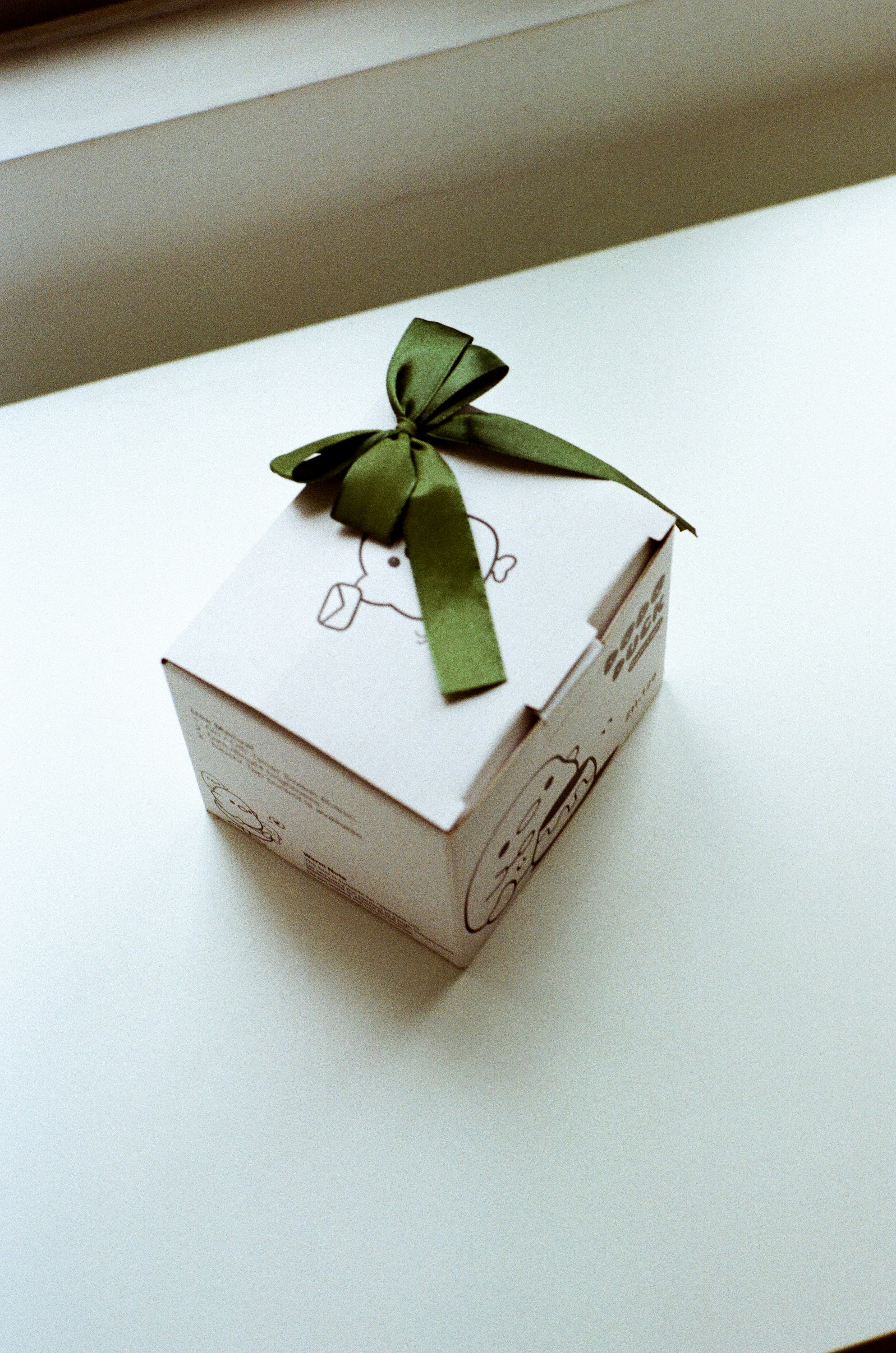 A white gift box with a green ribbon bow.