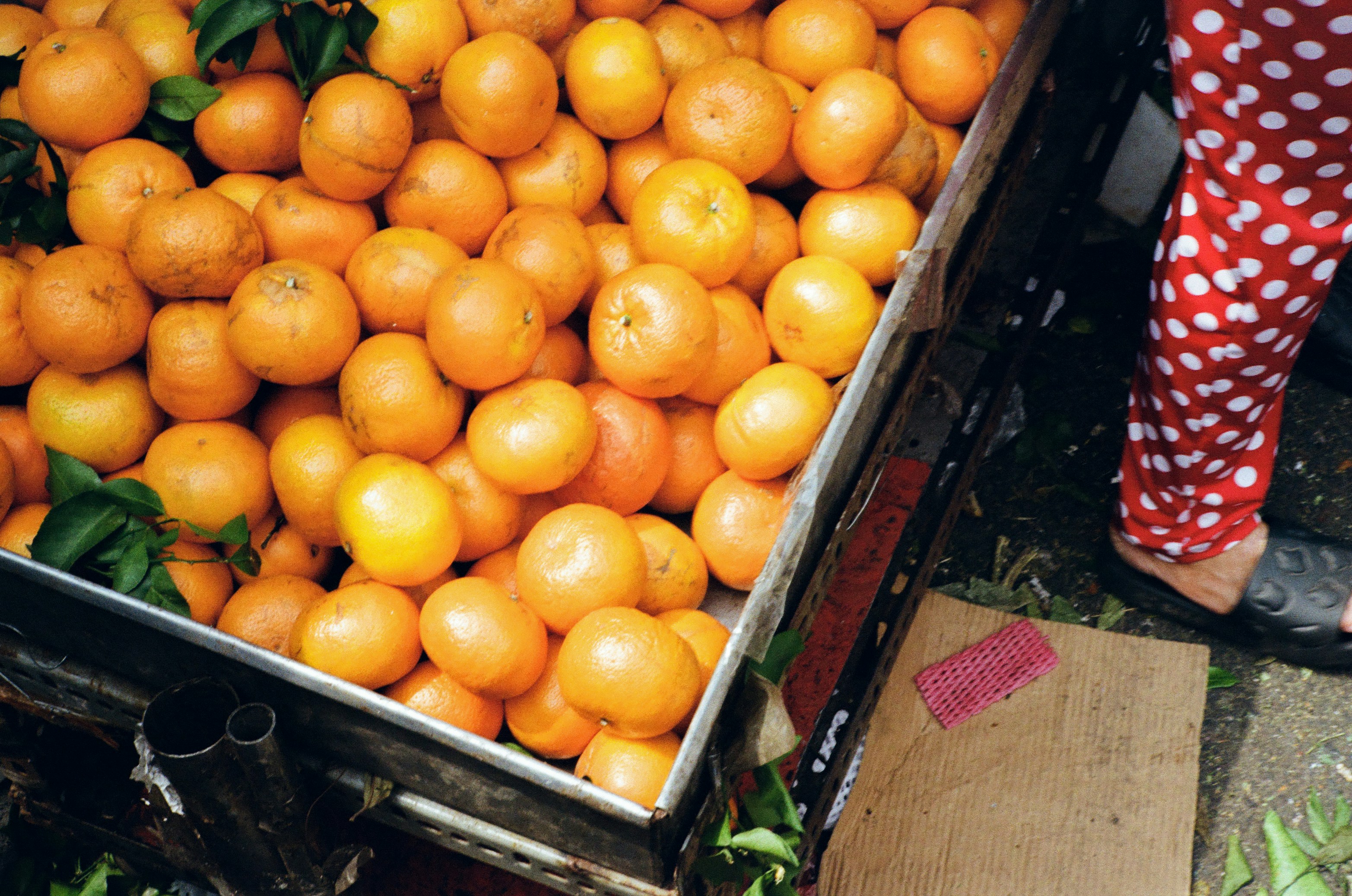 A bin full of fresh, ripe oranges at a market.