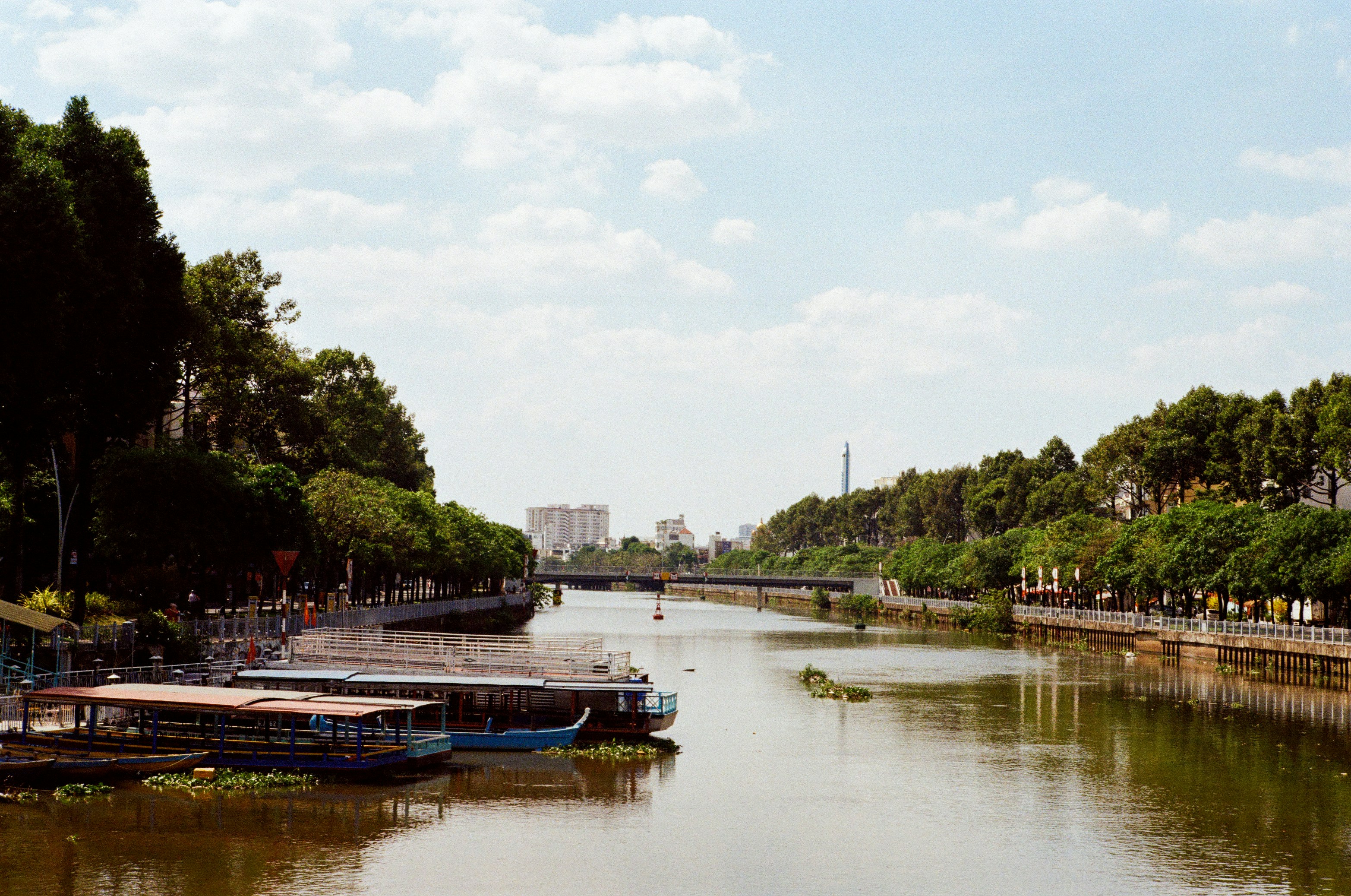 Boats docked on a wide river with lush green trees.