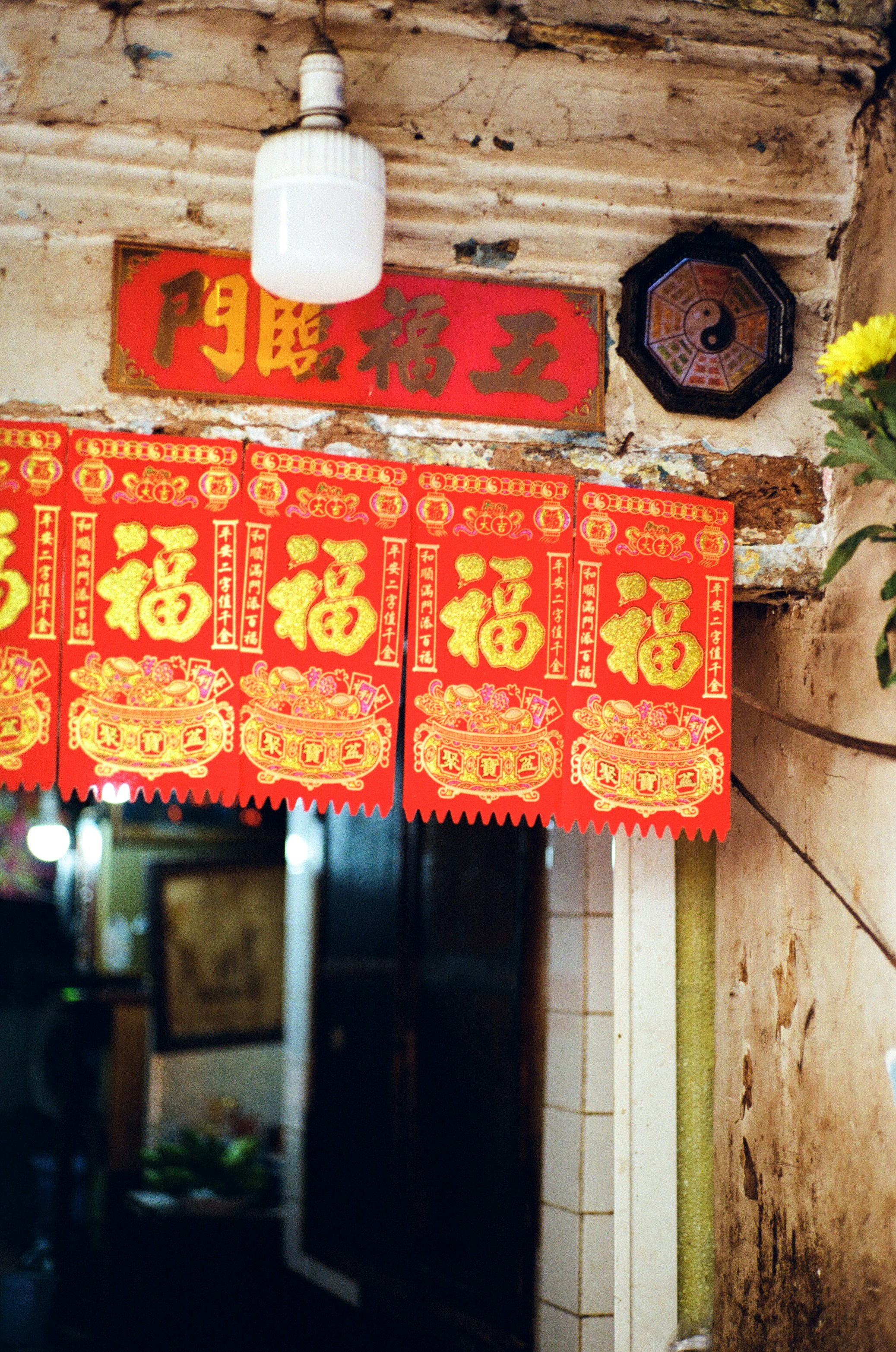 Red banners with golden chinese characters hang above doorway.