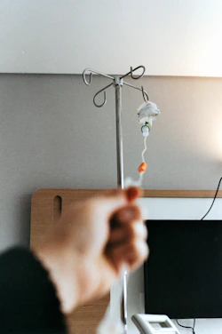 Hand reaching for iv drip stand in hospital room