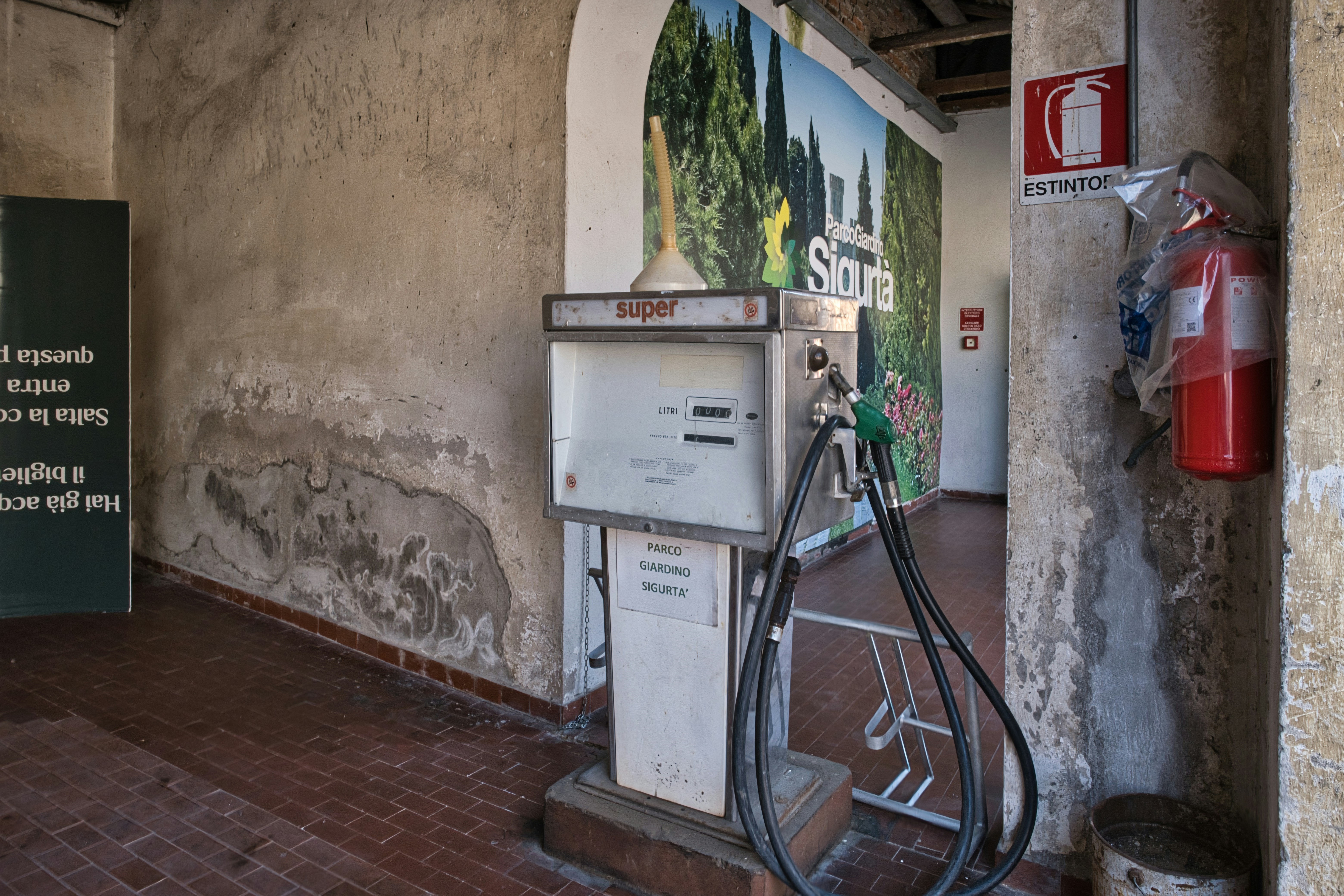 Vintage gas pump with fire extinguisher nearby.