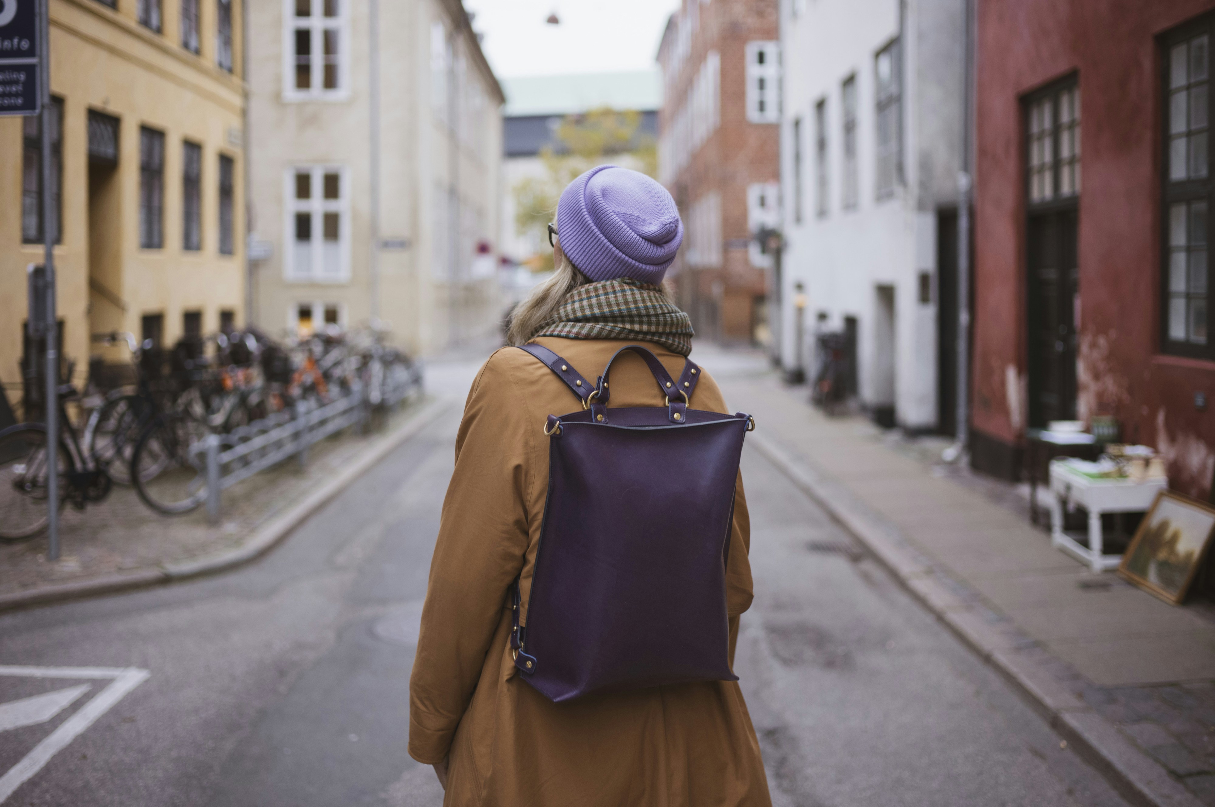 Woman with backpack walks down a european street.