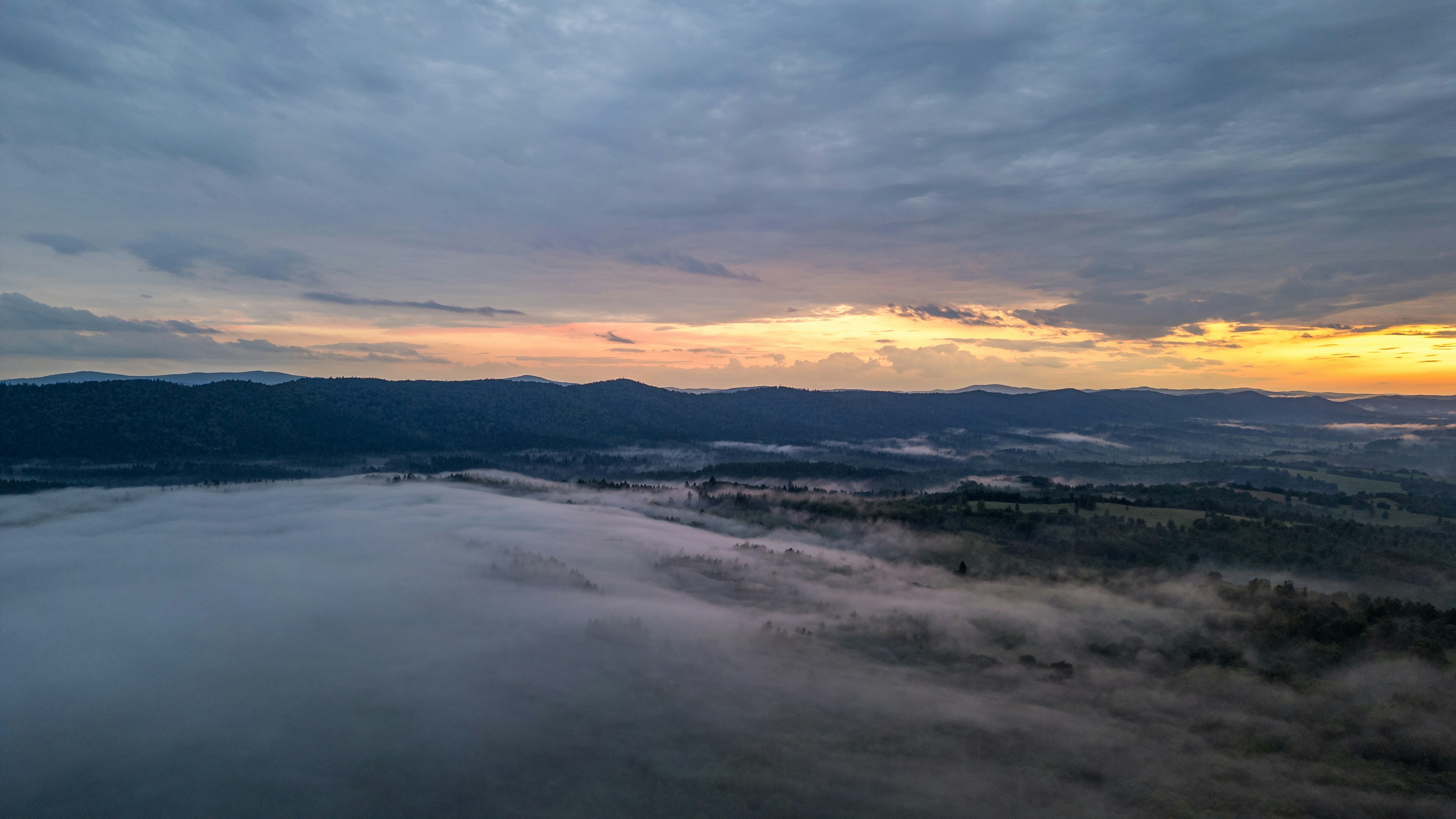 Amanecer sobre un valle brumoso con montañas lejanas.