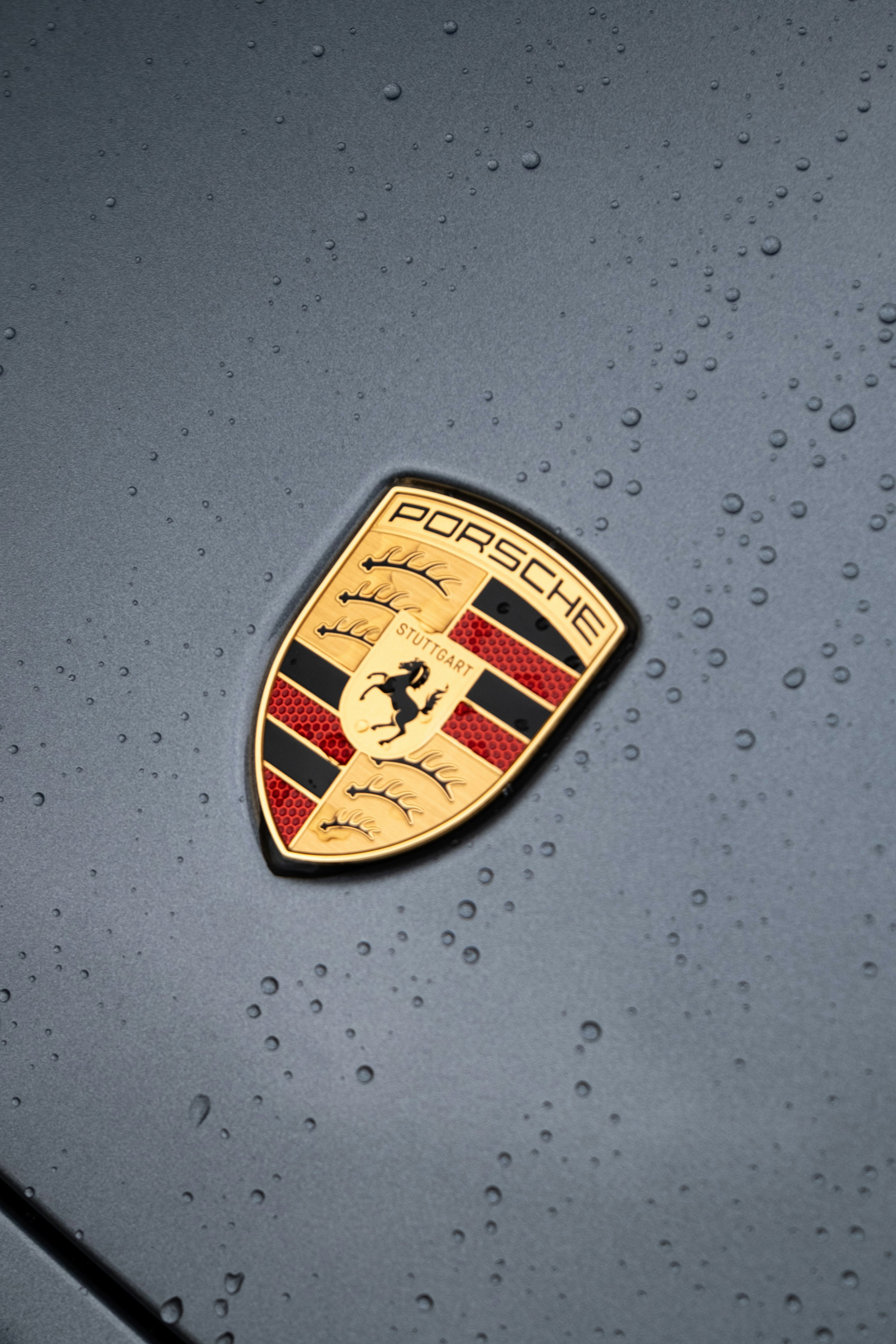 Emblema de Porsche en superficie mojada de coche