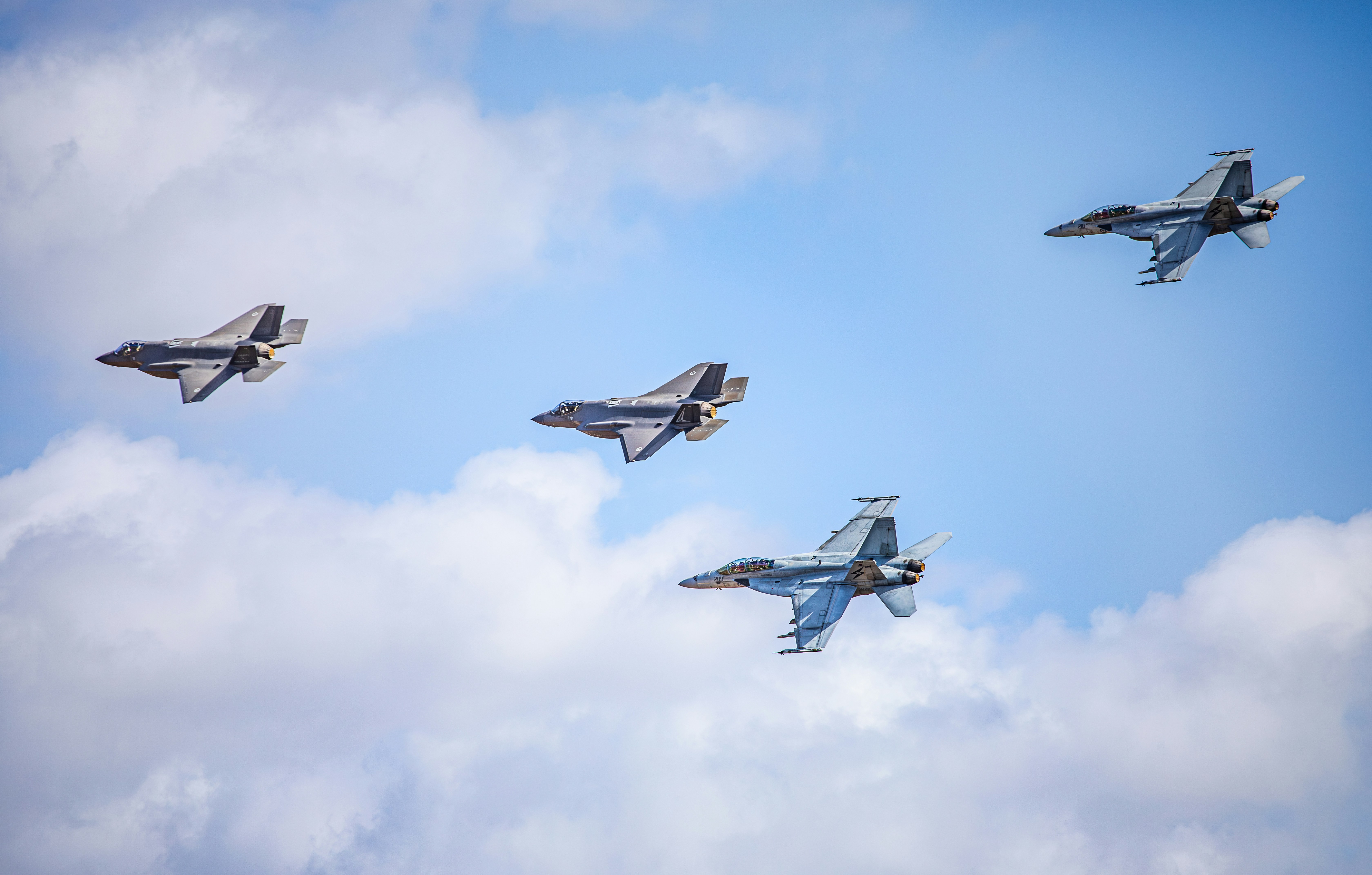 Four fighter jets flying in formation against a cloudy sky