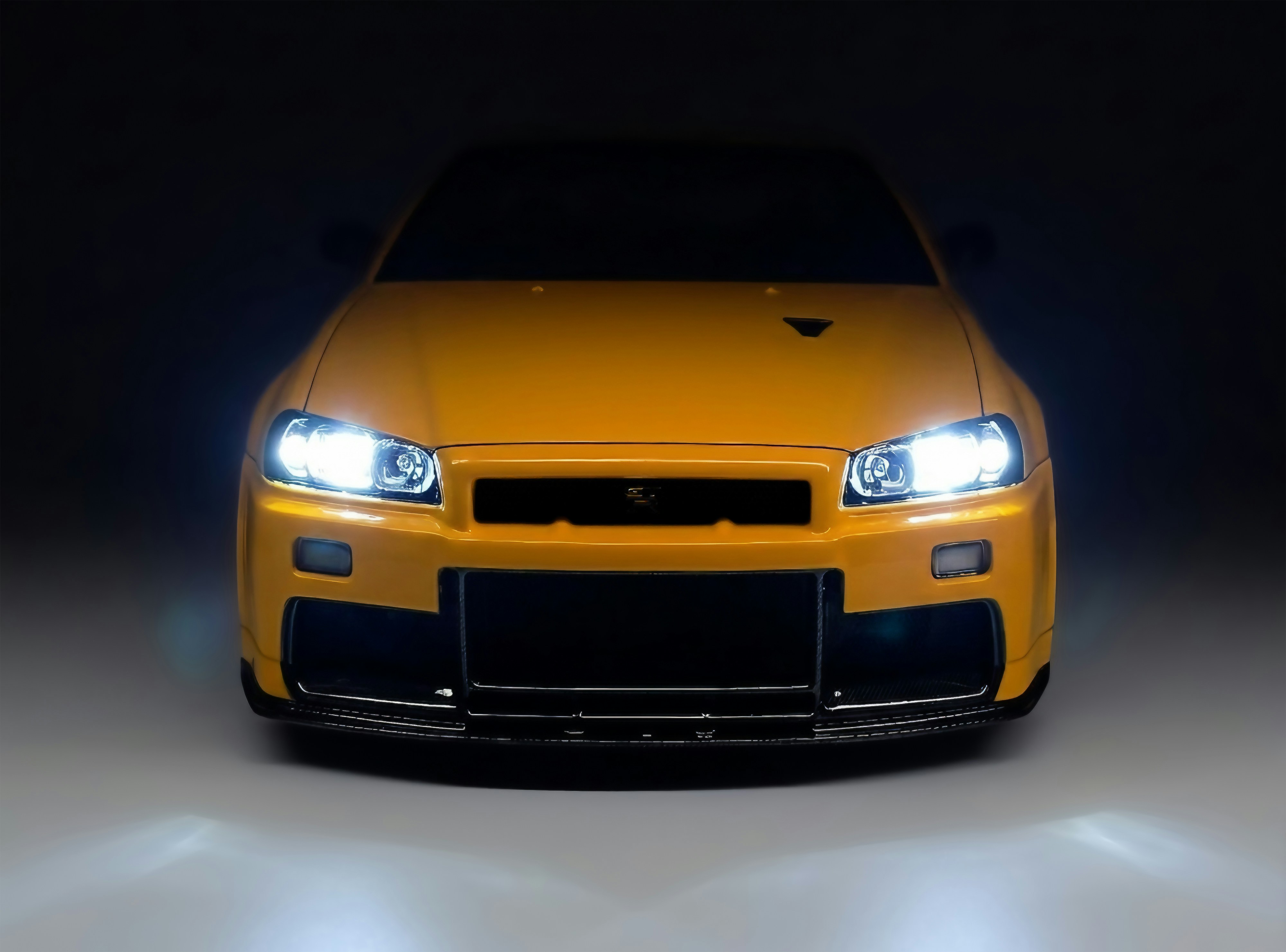 Front view of a yellow sports car with headlights on