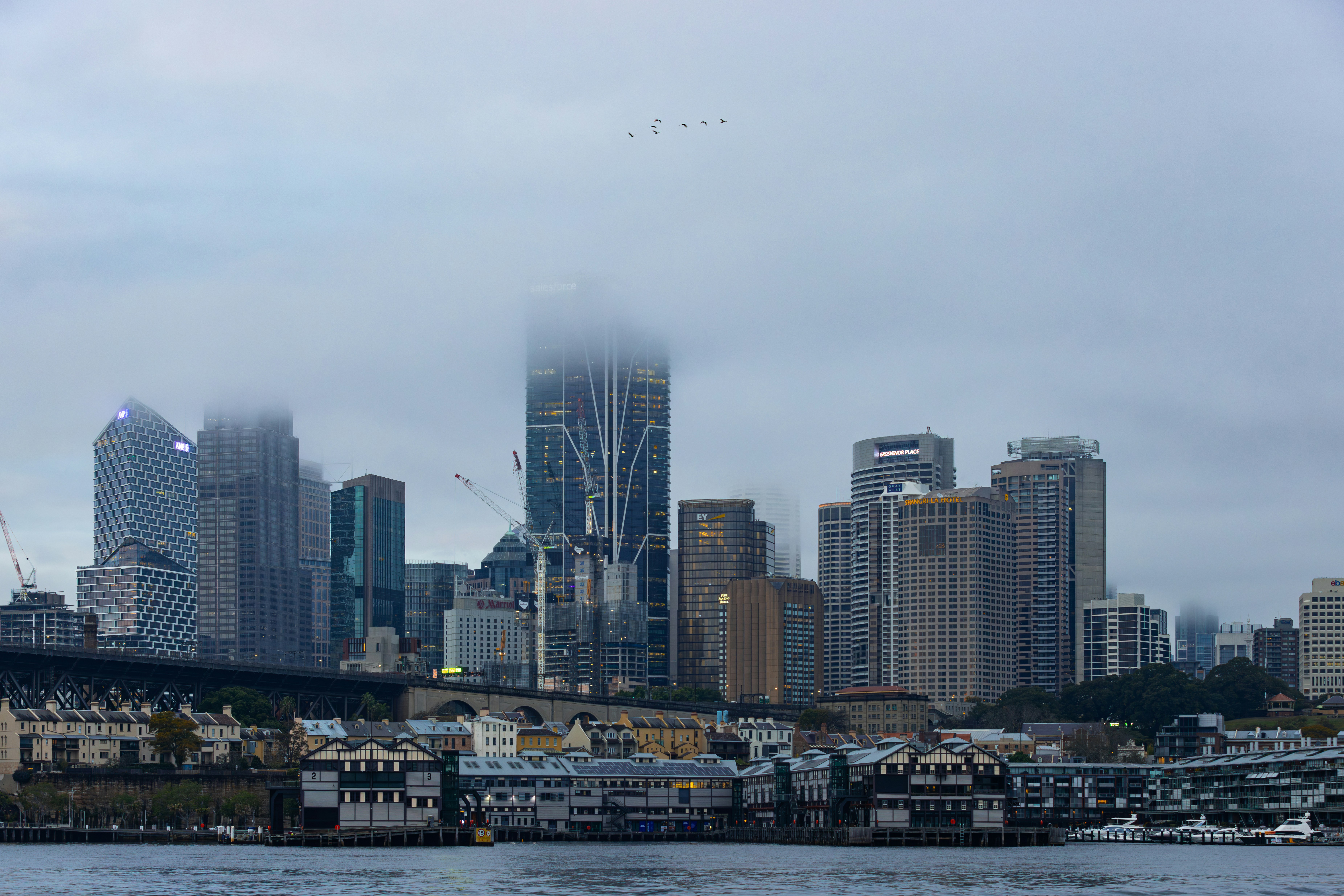 City skyline partially obscured by clouds over water.