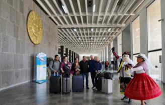 Tourists with luggage watch performers in traditional attire.