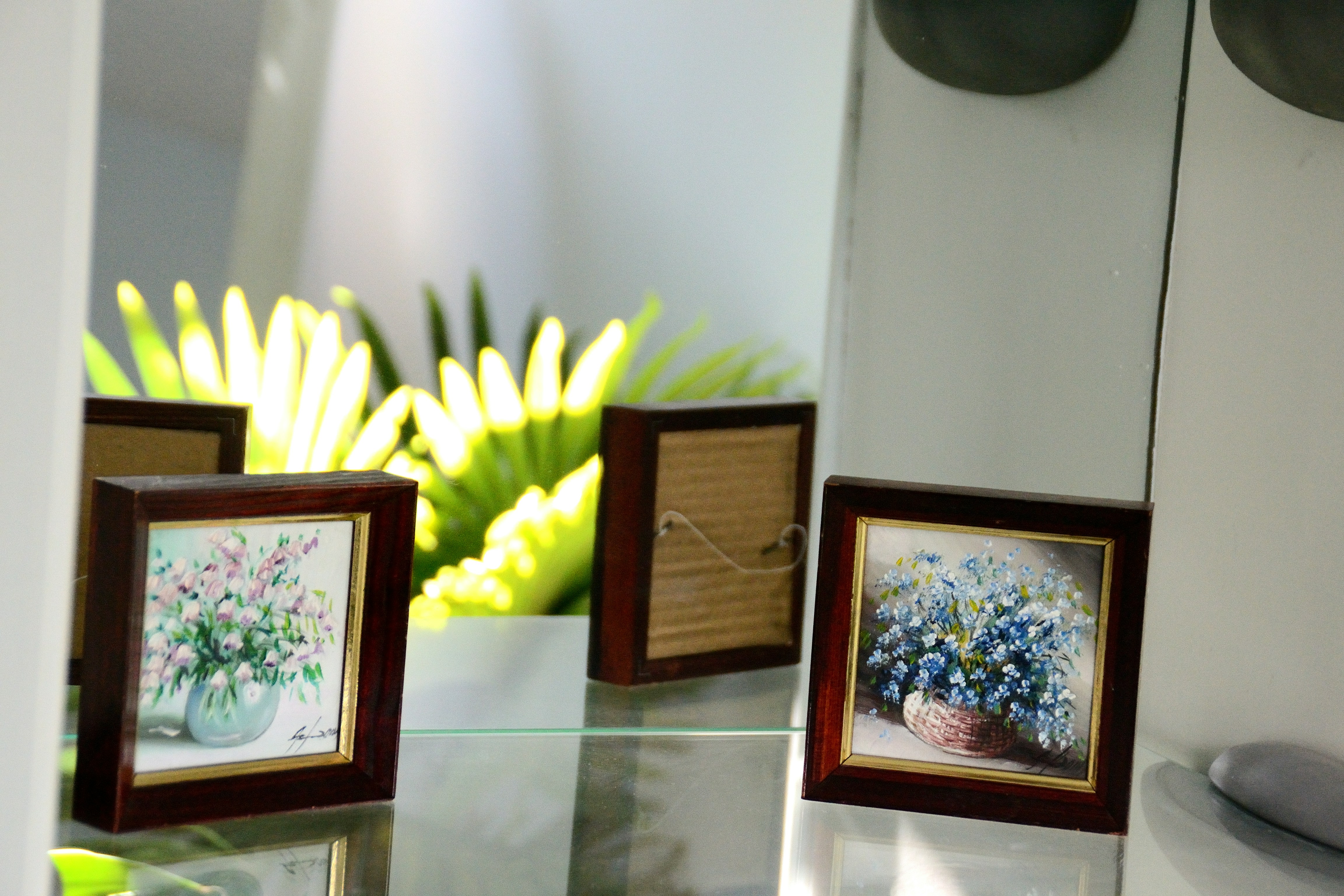 Two framed floral paintings on a shelf