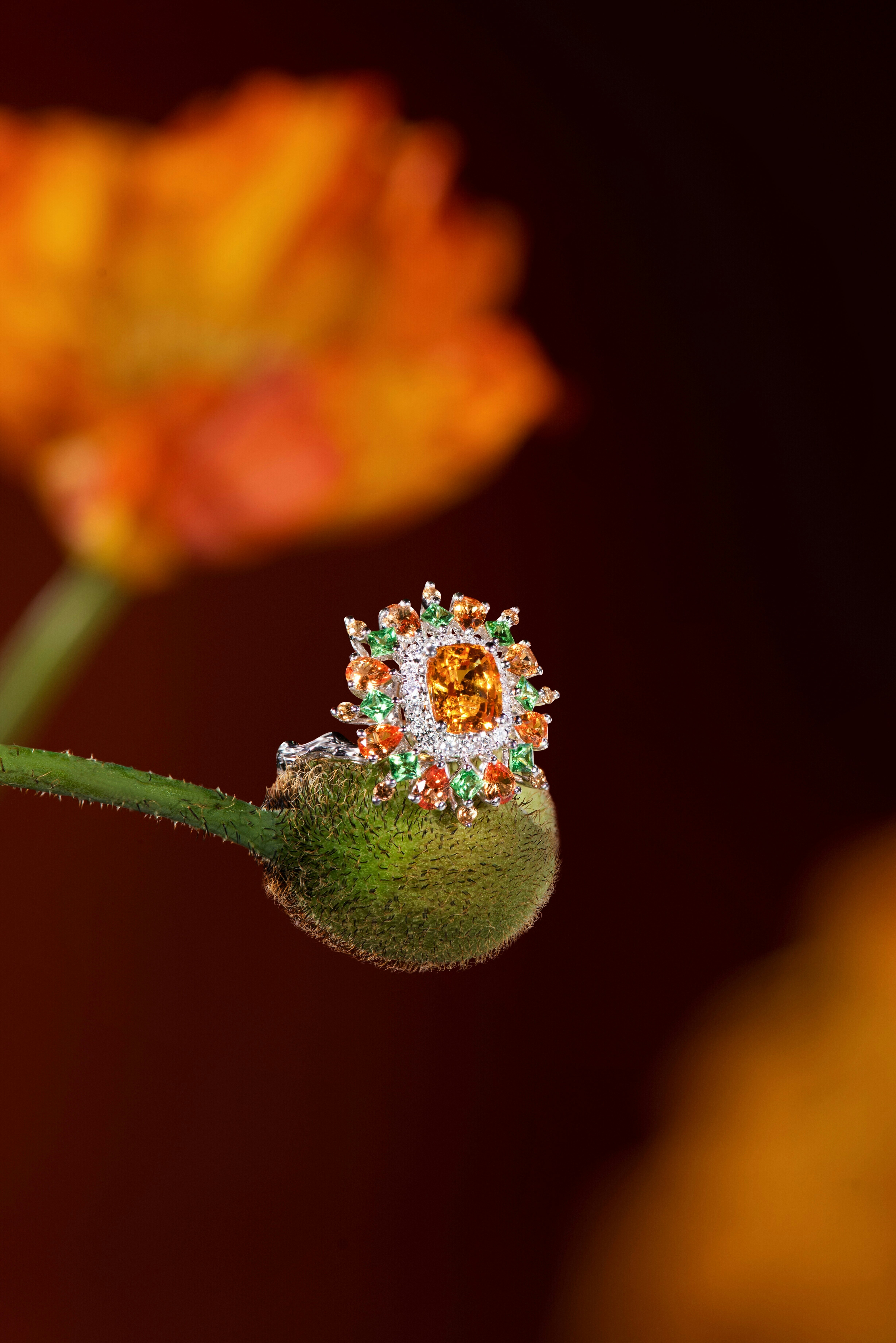 A sparkling ring rests on a green poppy bud.
