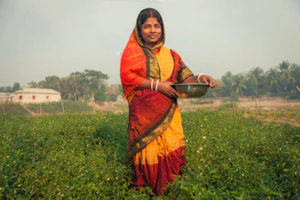 Woman in traditional clothing holding a bowl in a field