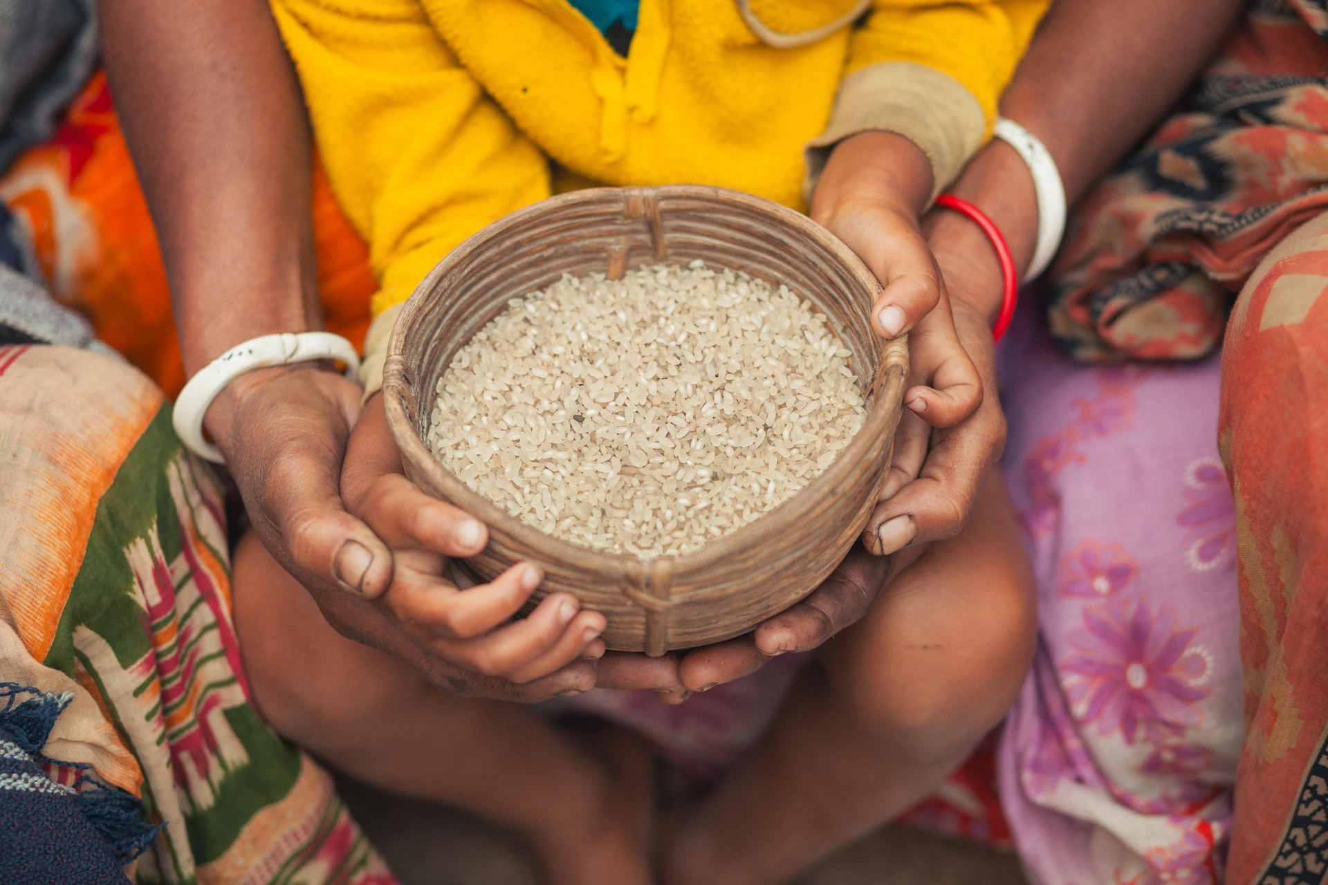 Hands holding a bowl of rice.