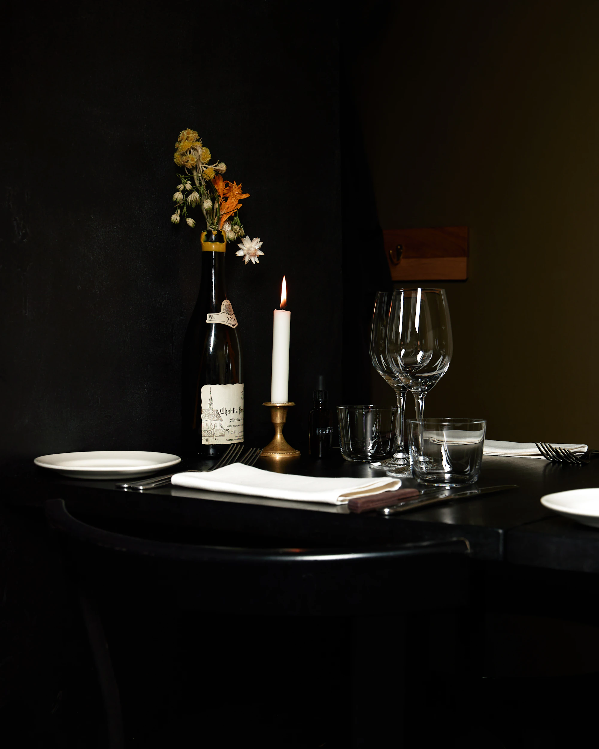 A candle-lit table set with wine and flowers