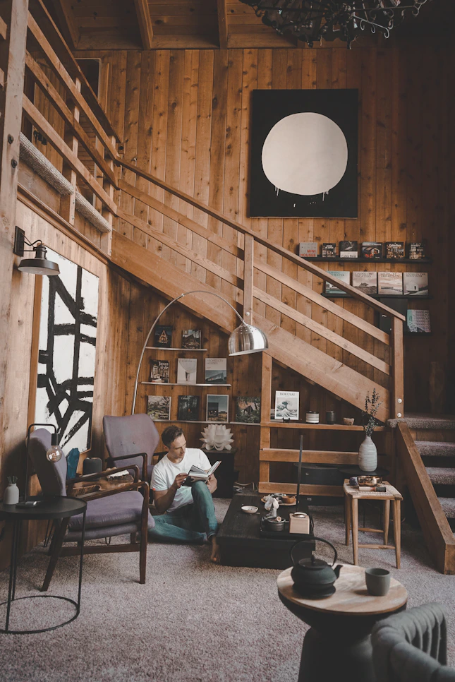 Man reading a book in a cozy wooden room.