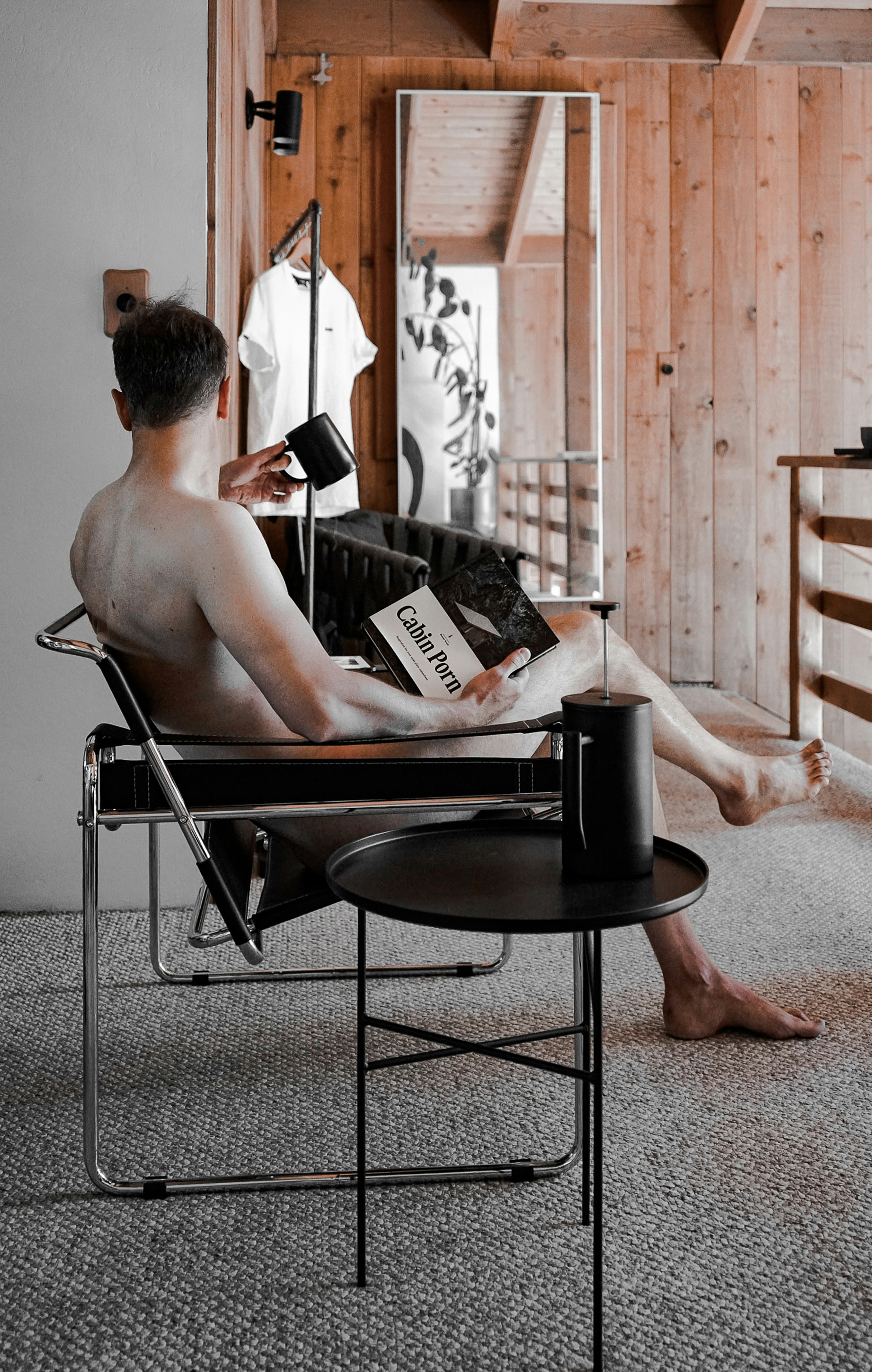 Mann sitzt auf dem Stuhl mit Kaffee und Buch