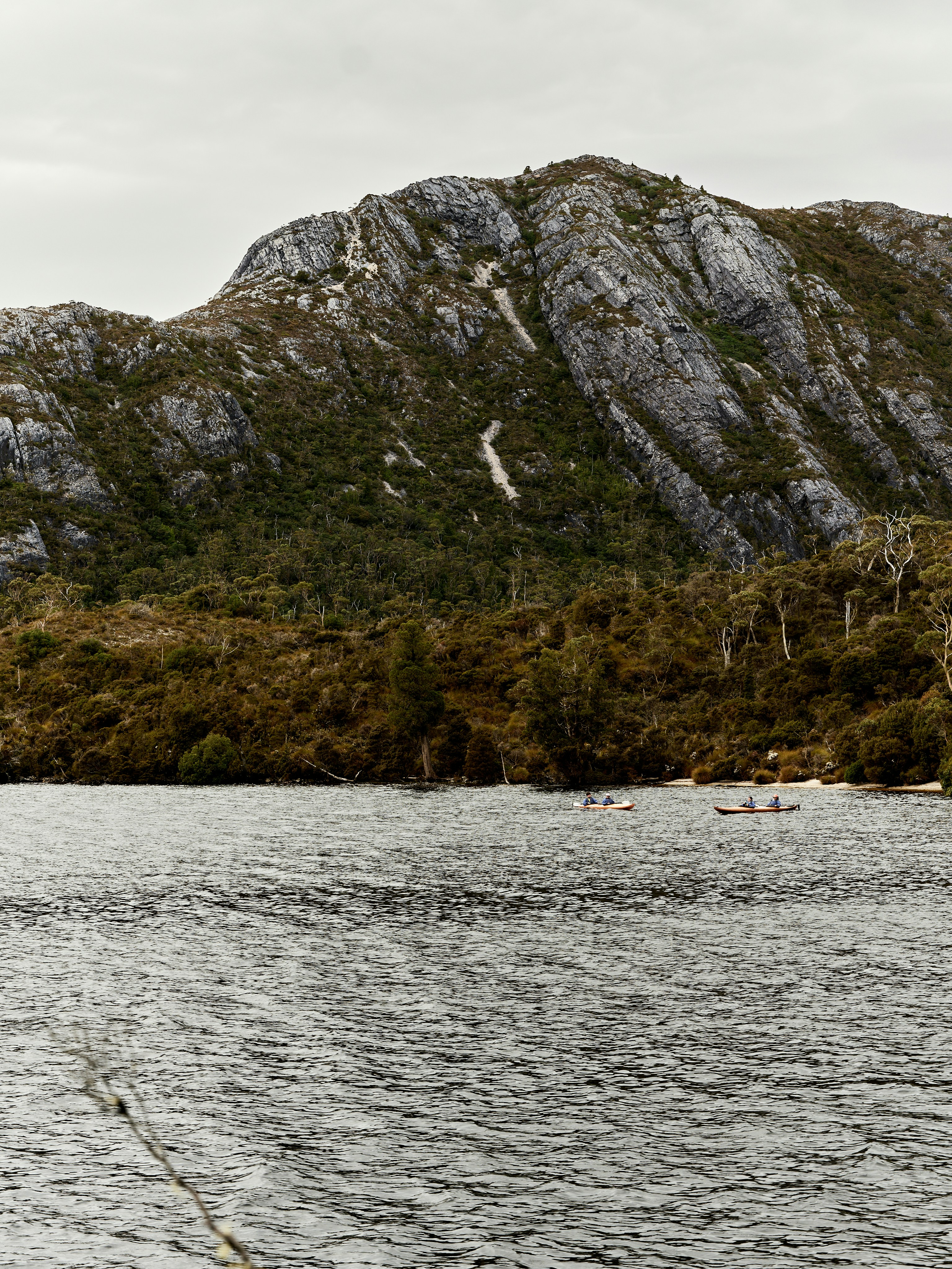 Kayaks on a calm lake with a rocky mountain background