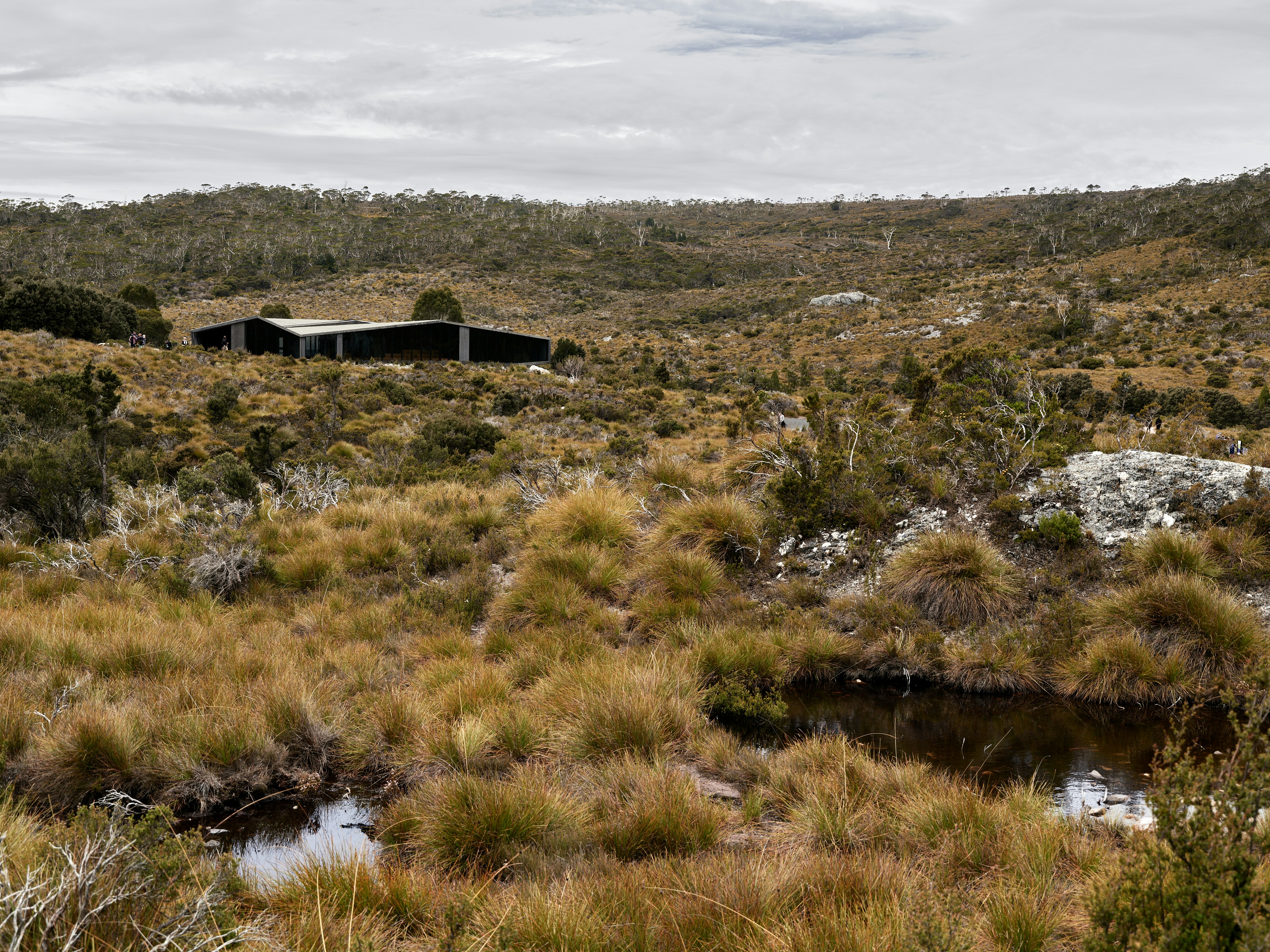 A remote hut nestled in a grassy, hilly landscape.