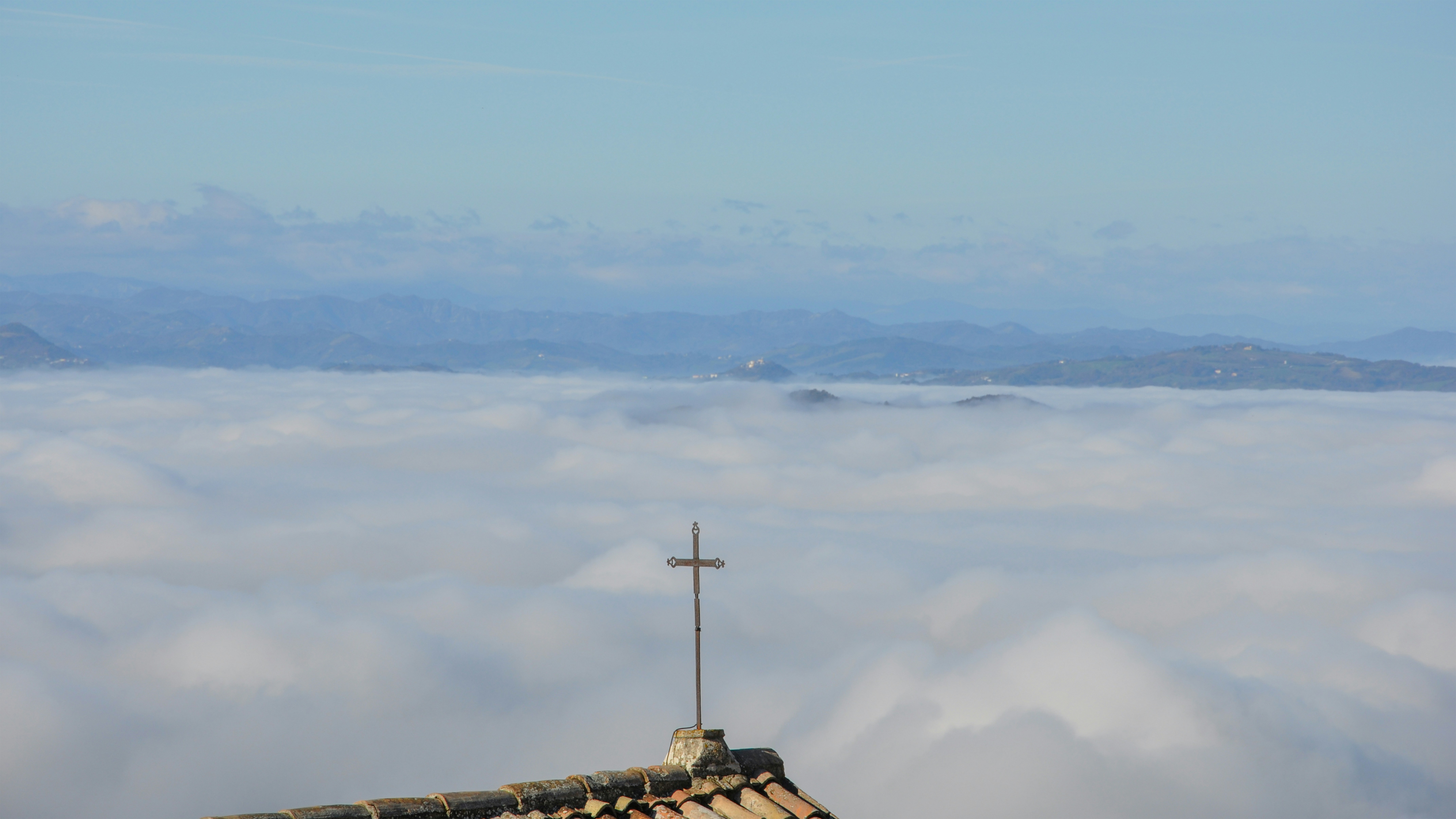 A cross stands above a sea of clouds