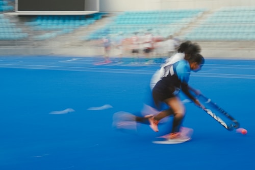 A hockey player in motion on a blue field