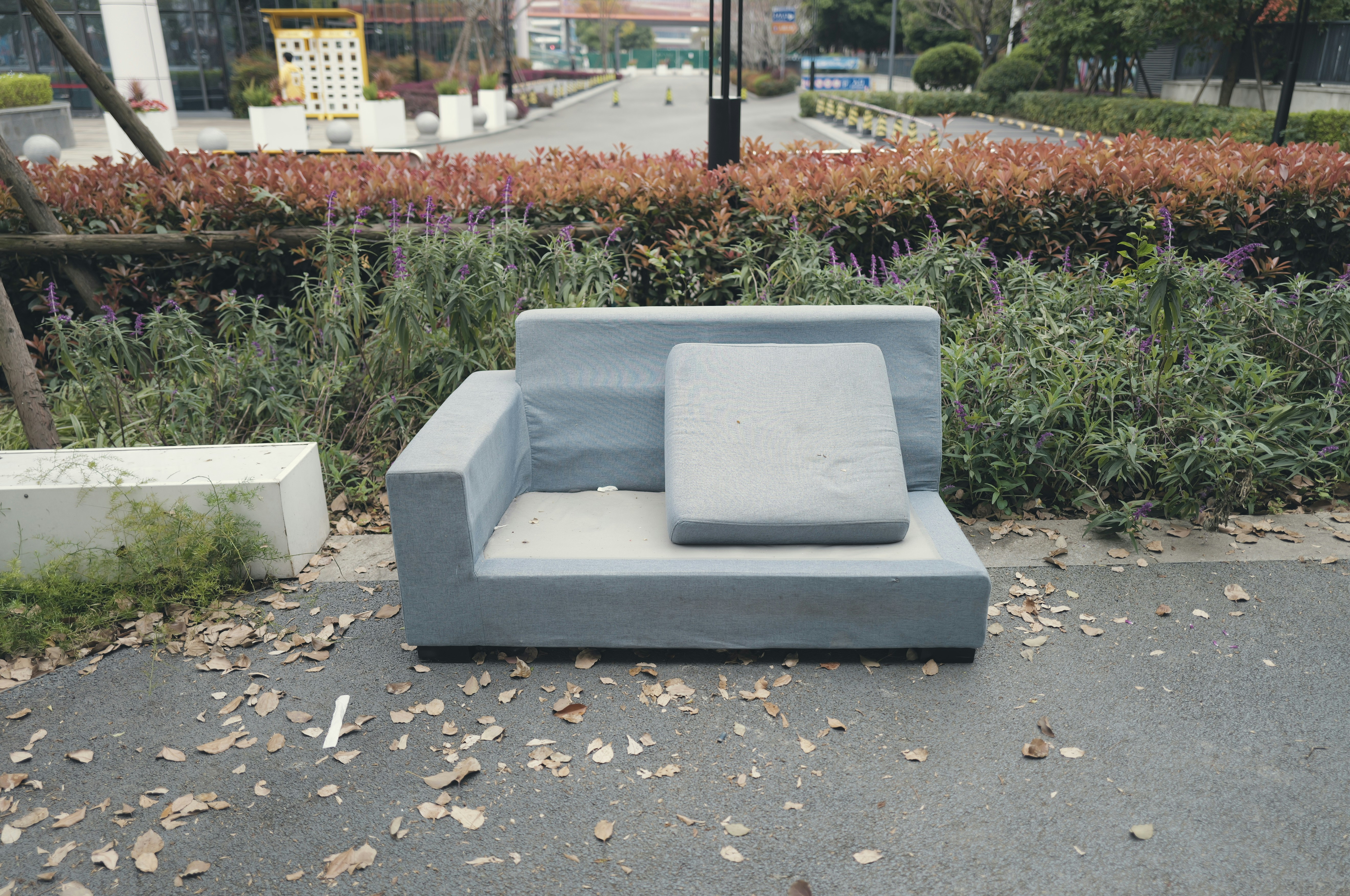 A grey sofa sits on an outdoor paved area.