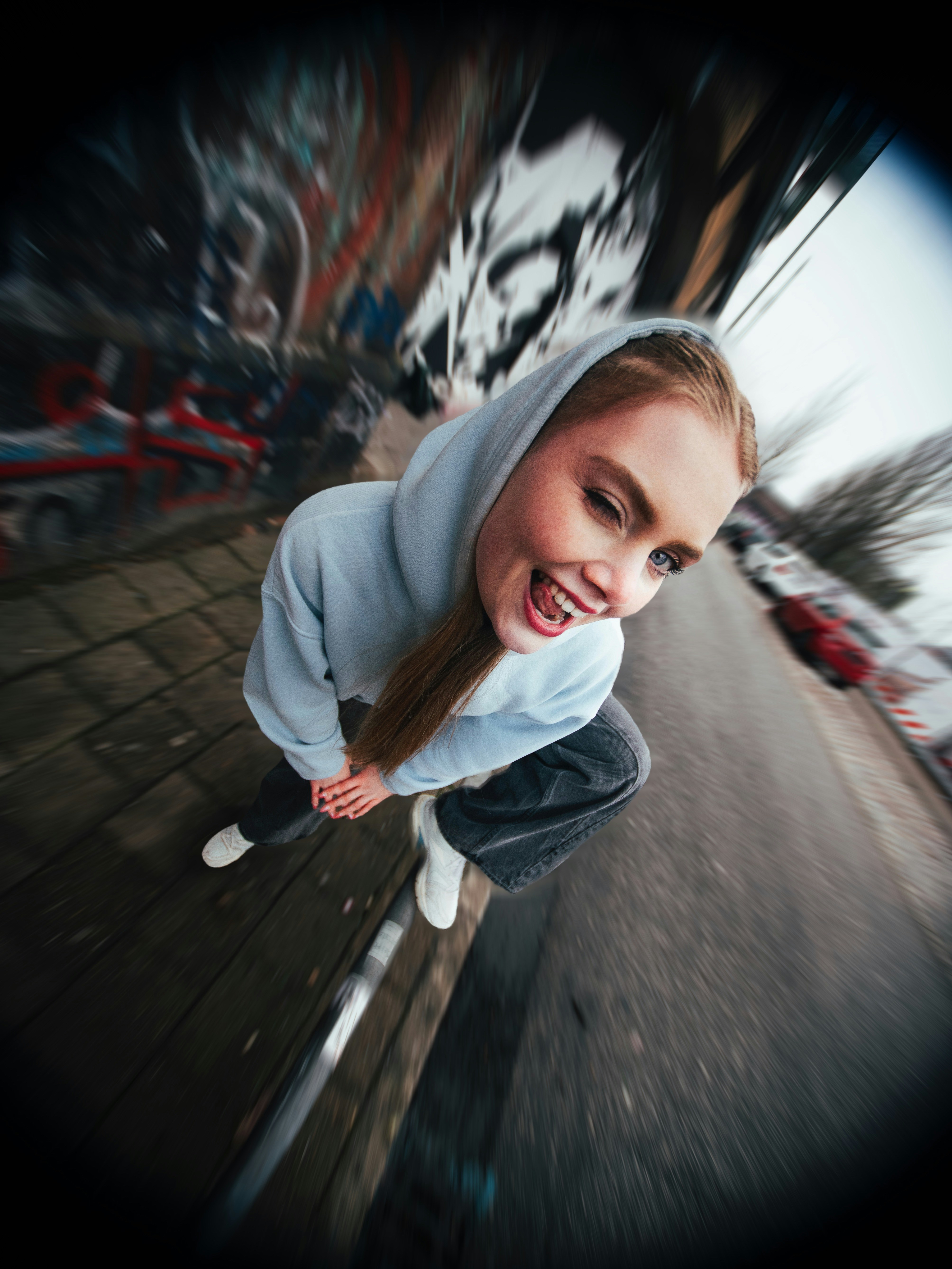 Die junge Frau zwinkert, während sie in der Nähe der Graffiti-Wand hockt.