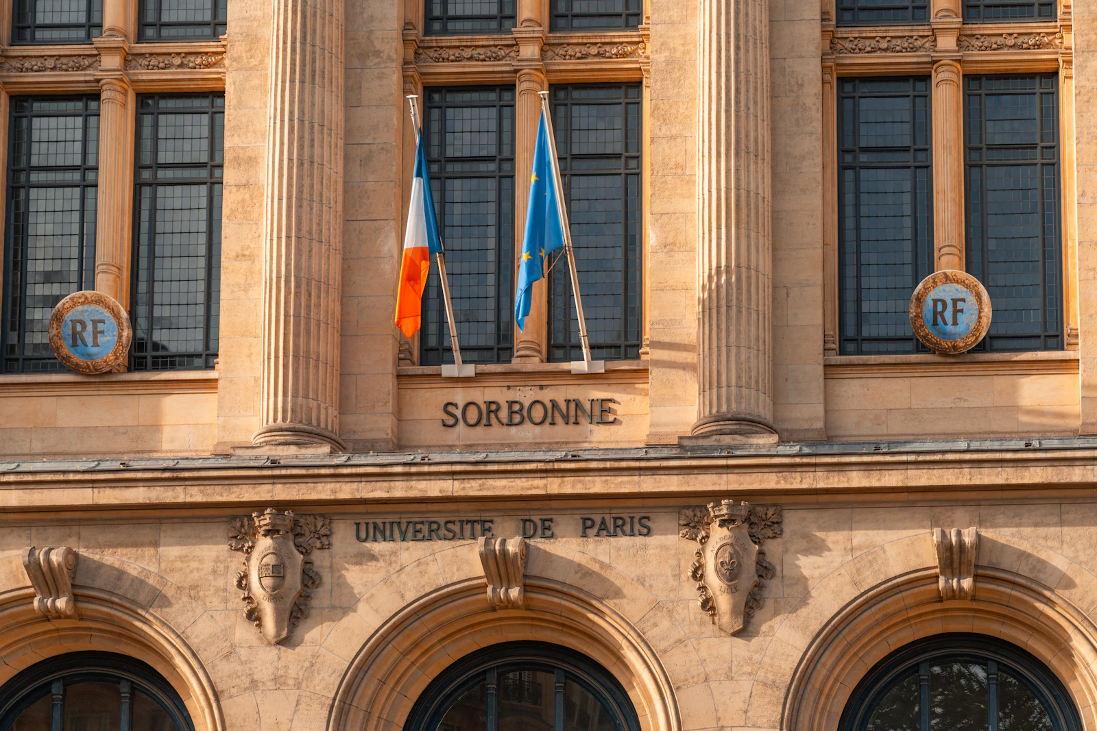 Facade of the Sorbonne university building with French flags, Paris, France
