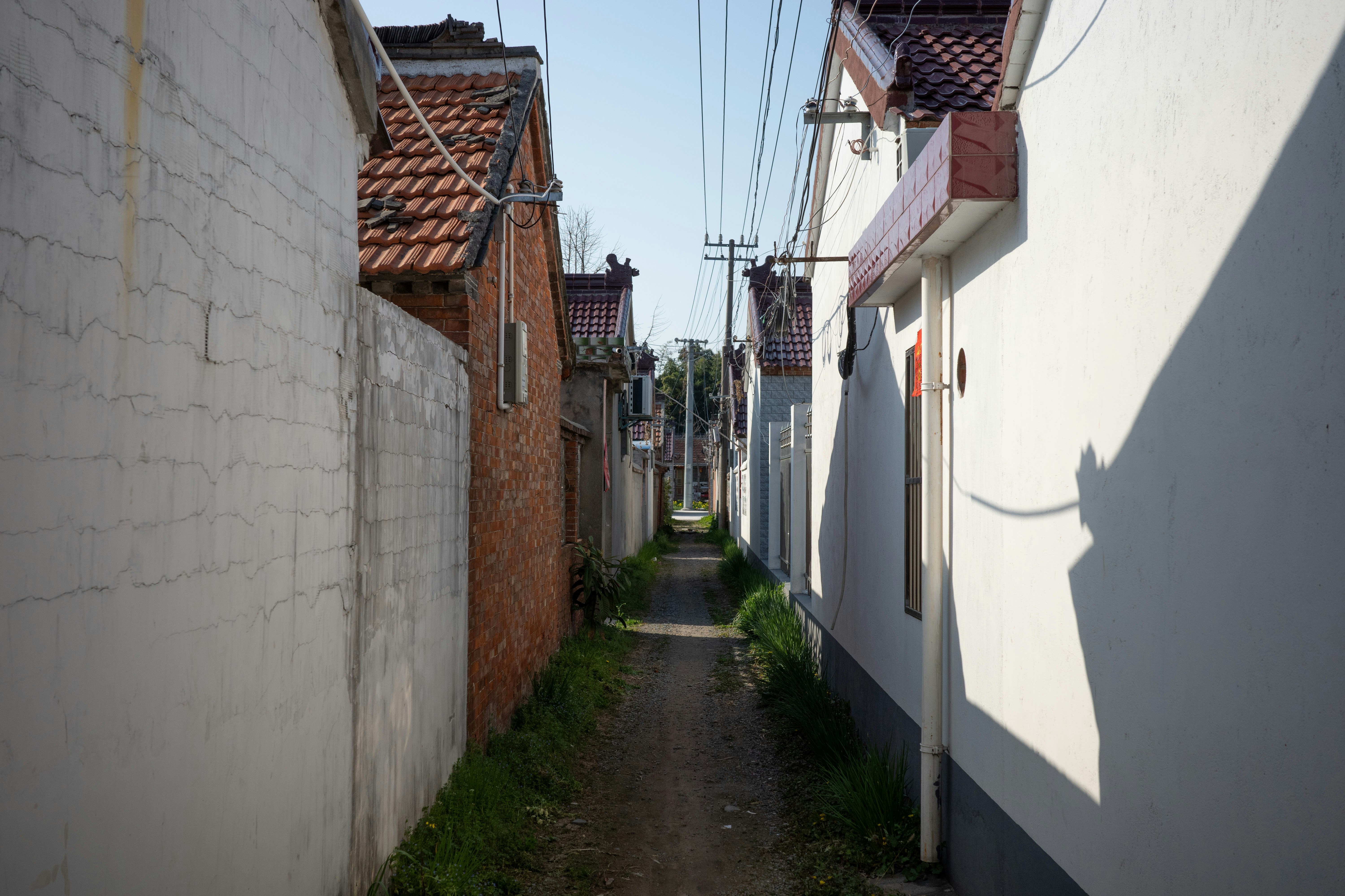 Narrow alleyway between white and brick buildings.