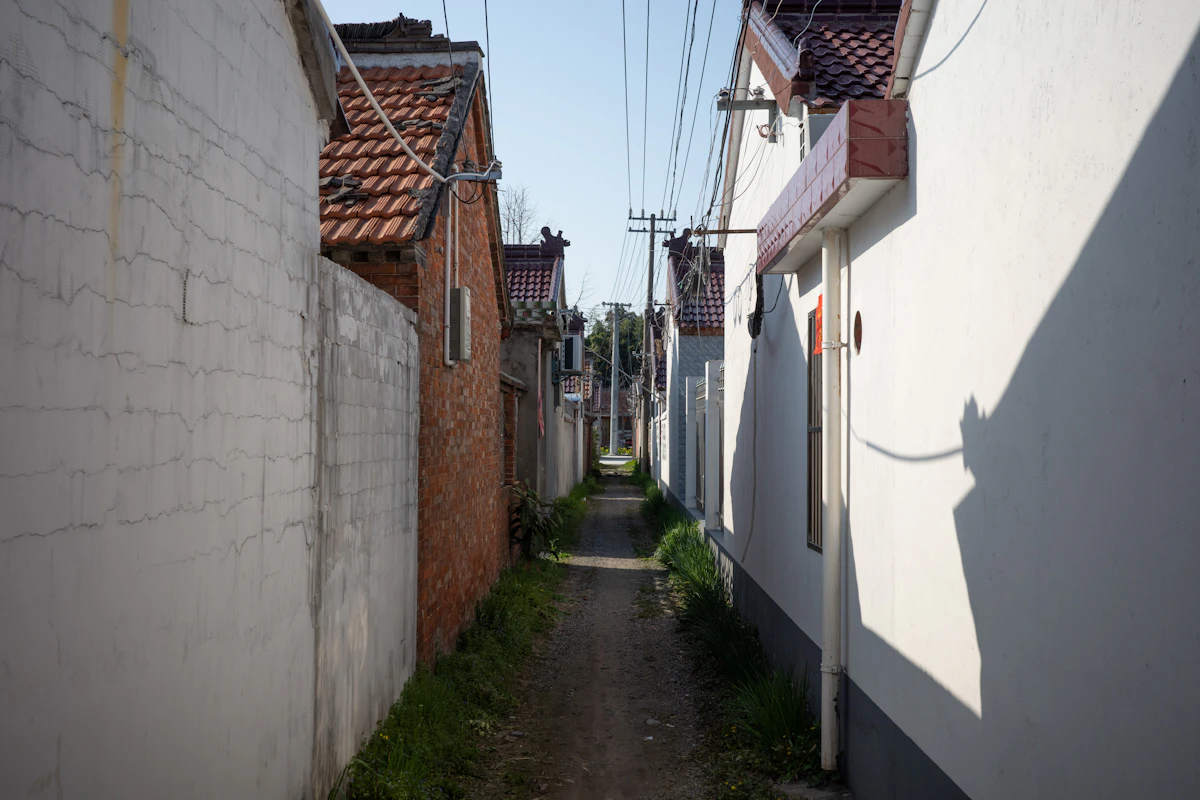 Lorong sempit di antara bangunan putih dan bata di permukiman