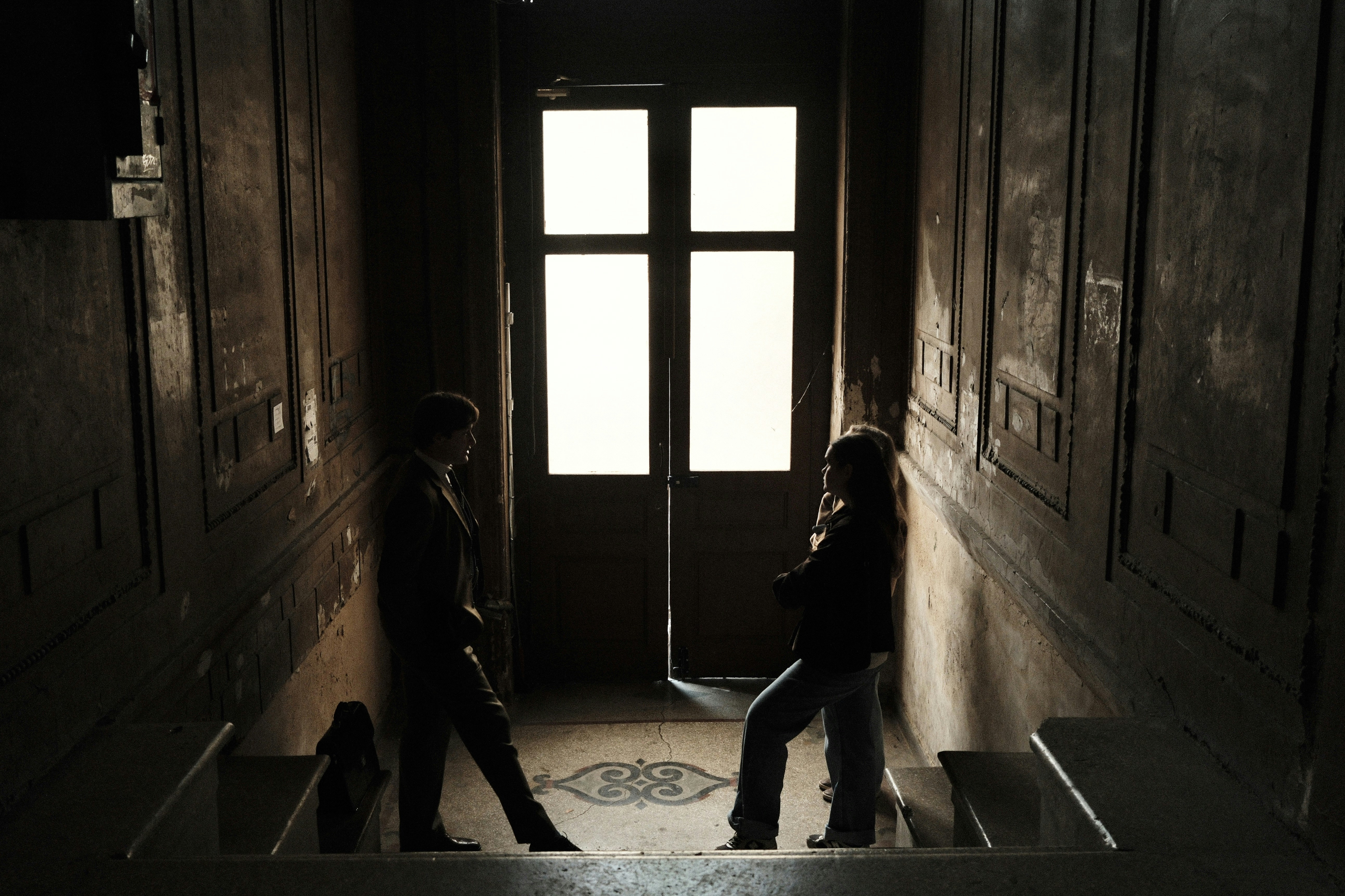 Two people standing in a dimly lit hallway.
