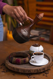 Pouring coffee from a traditional jug into a cup.