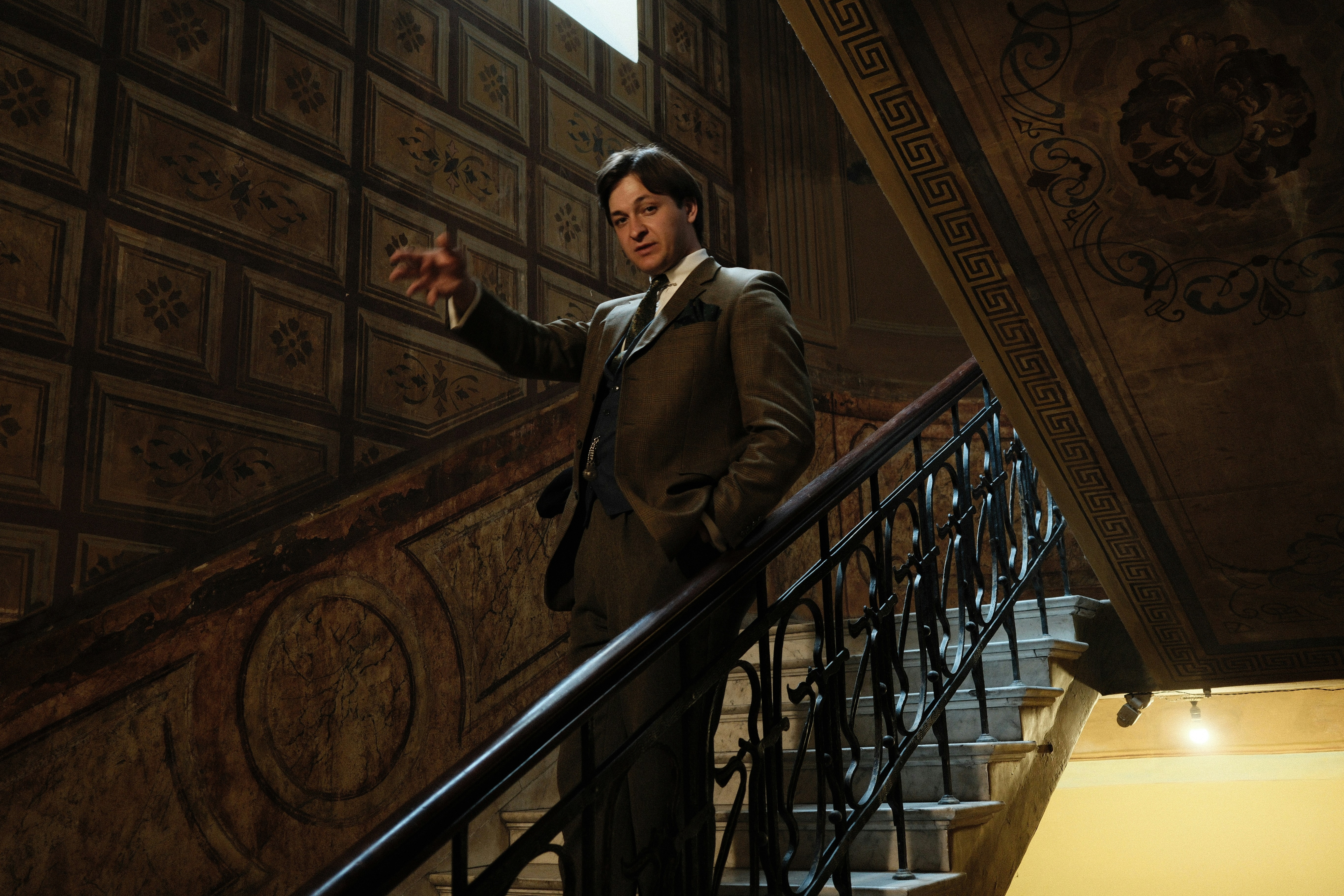 Man in vintage suit on ornate staircase