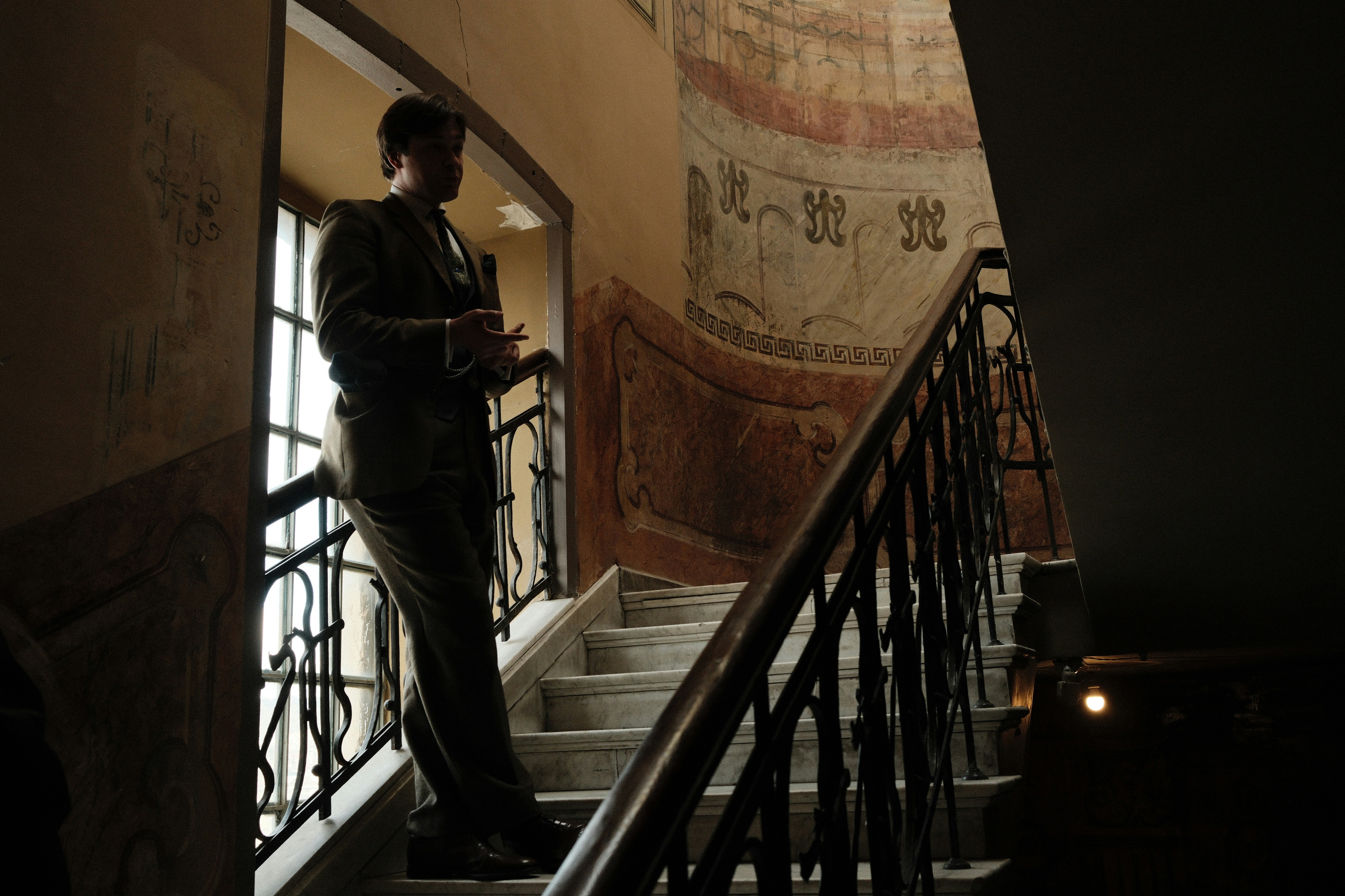 Man in suit standing on ornate staircase