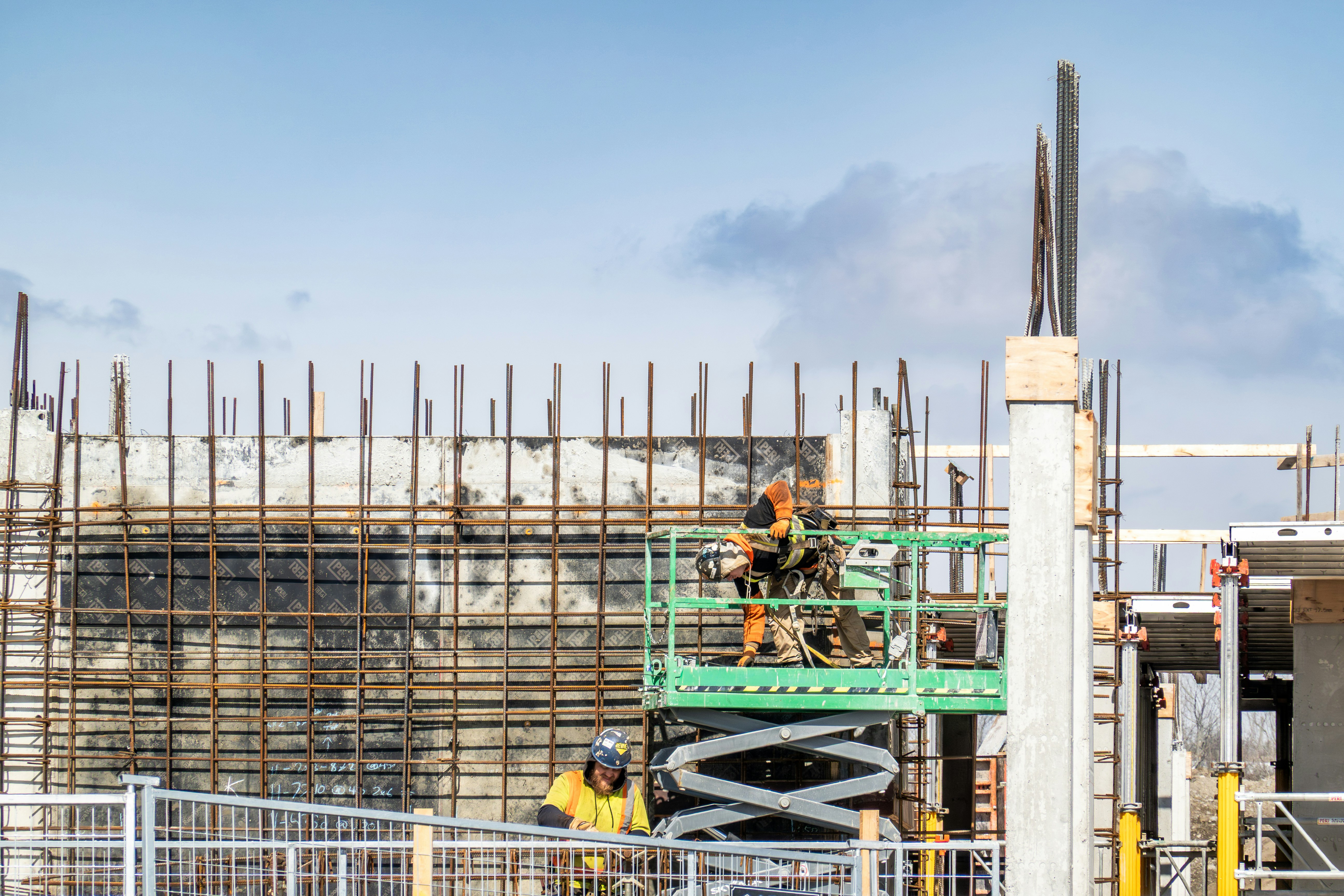 Construction workers on a scissor lift at a building site.