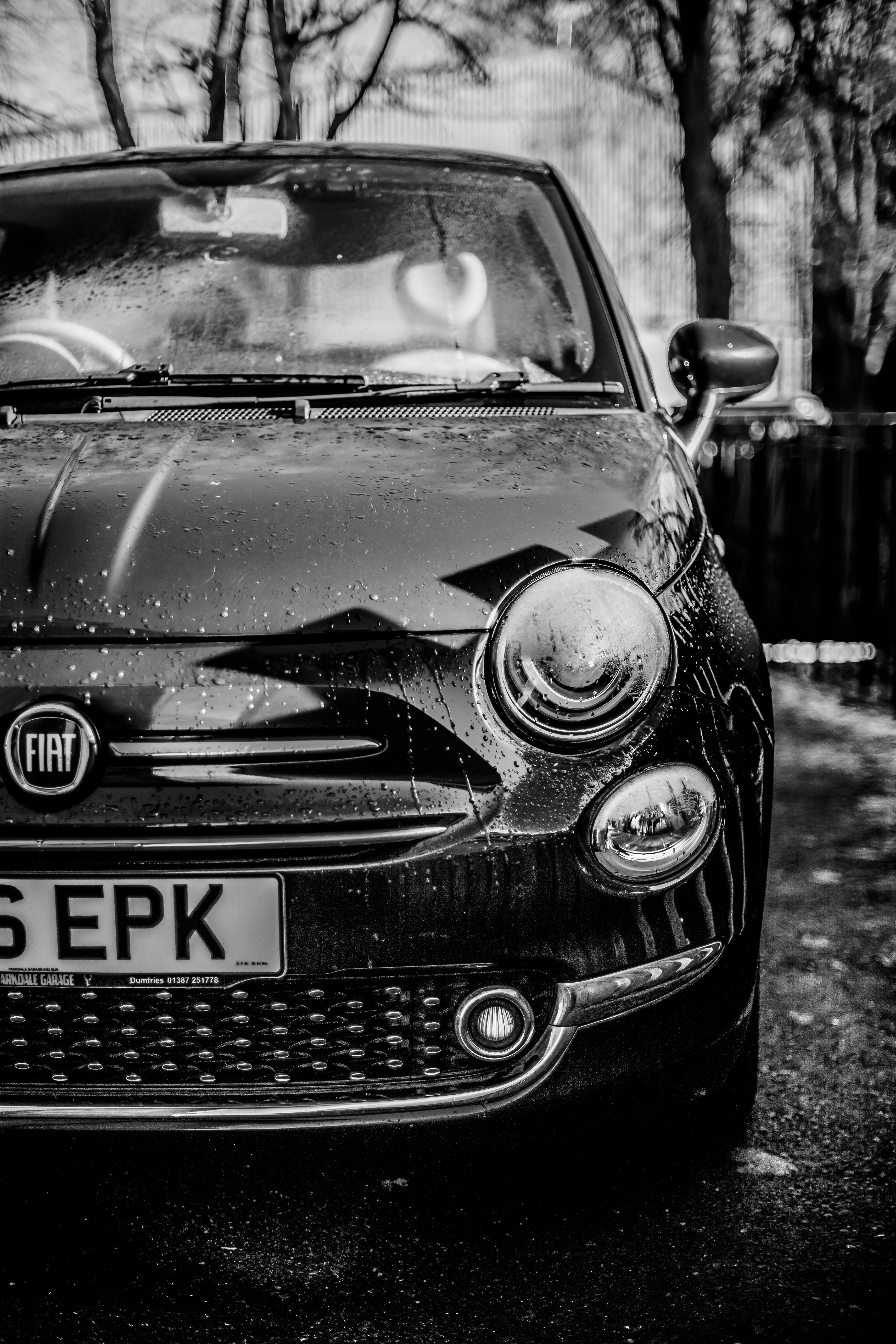 A black fiat 500 car with water droplets.