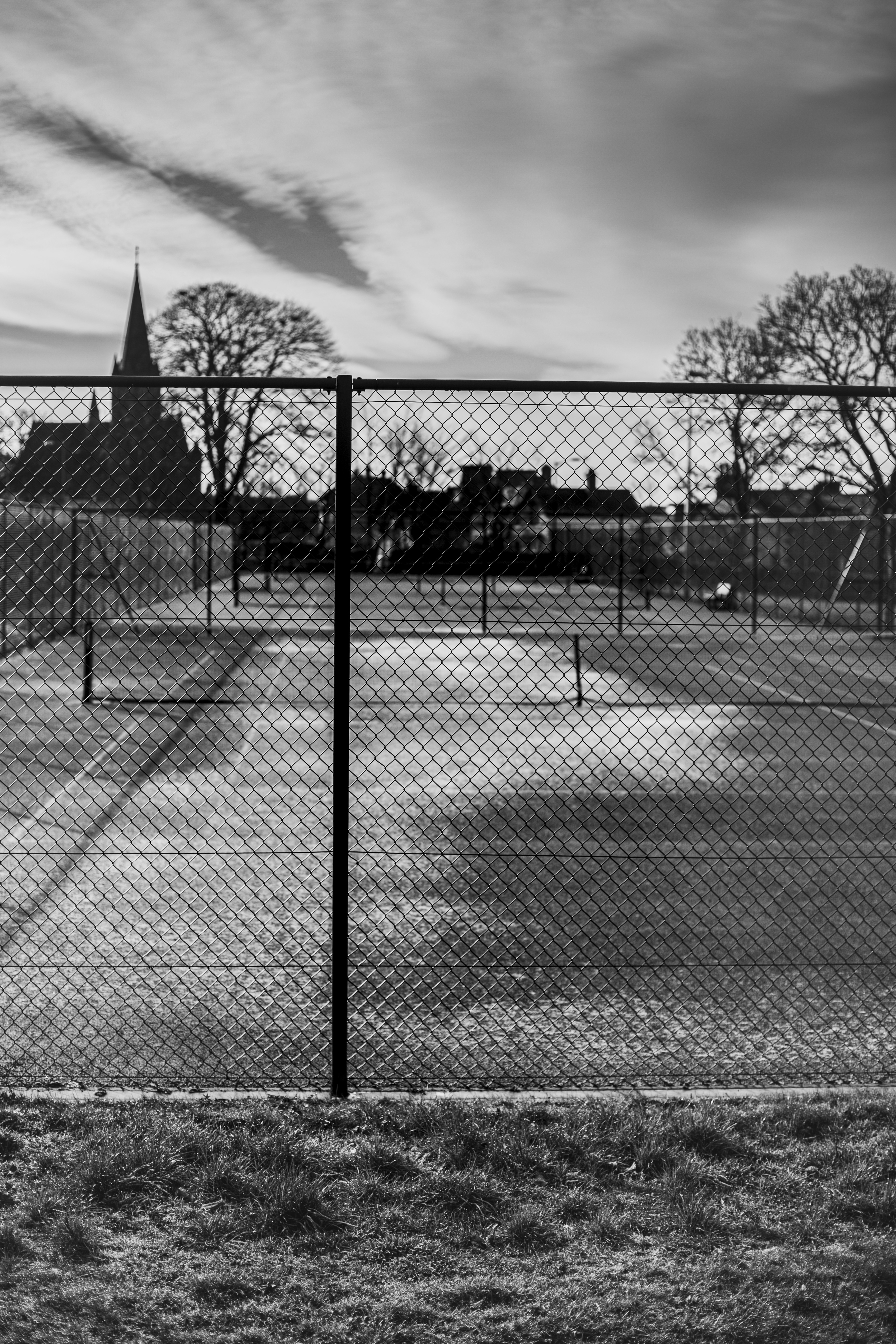 Empty tennis courts behind a chain-link fence