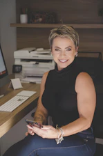 A smiling woman with short blonde hair using her phone.