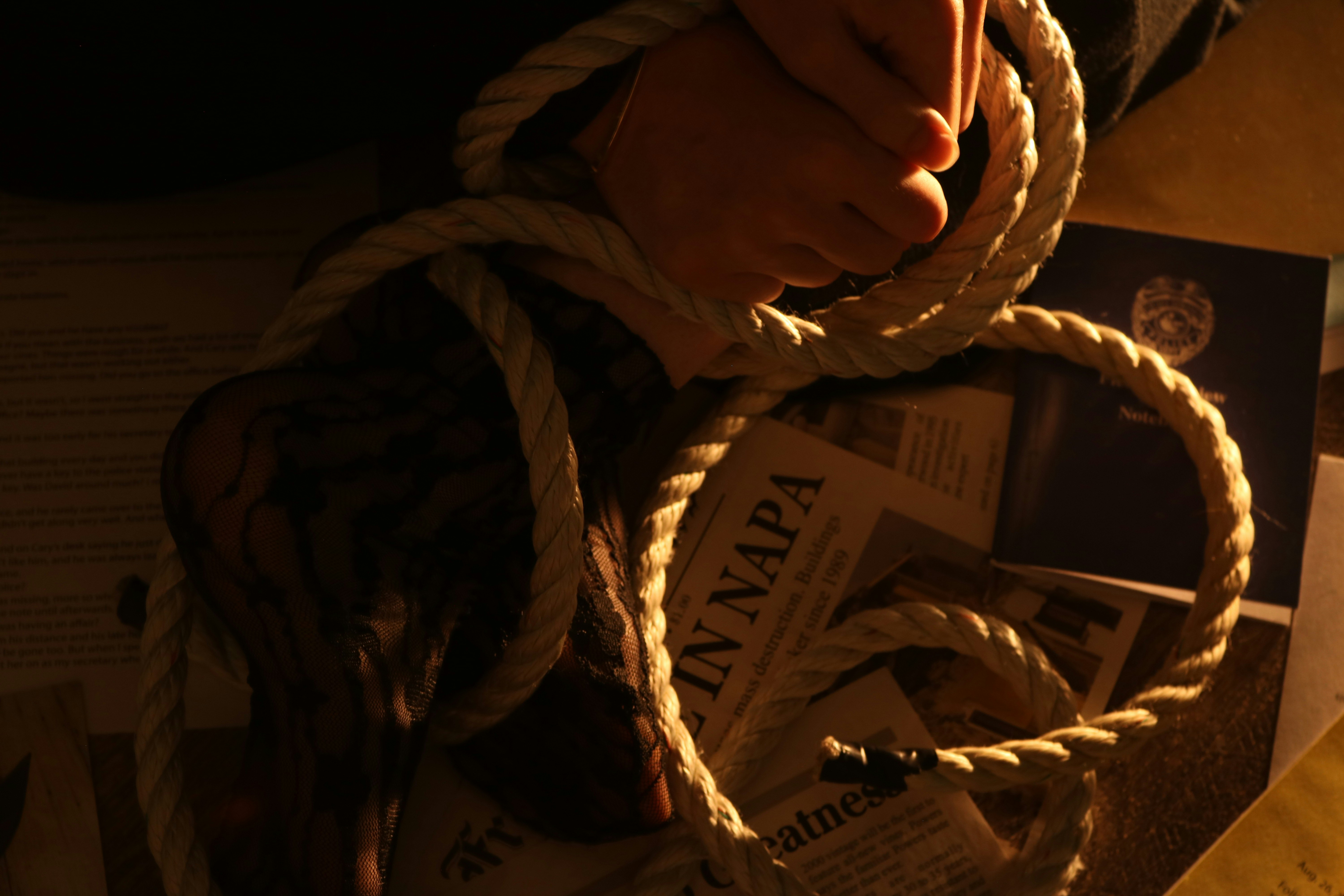 Hands tied with rope, papers scattered on table