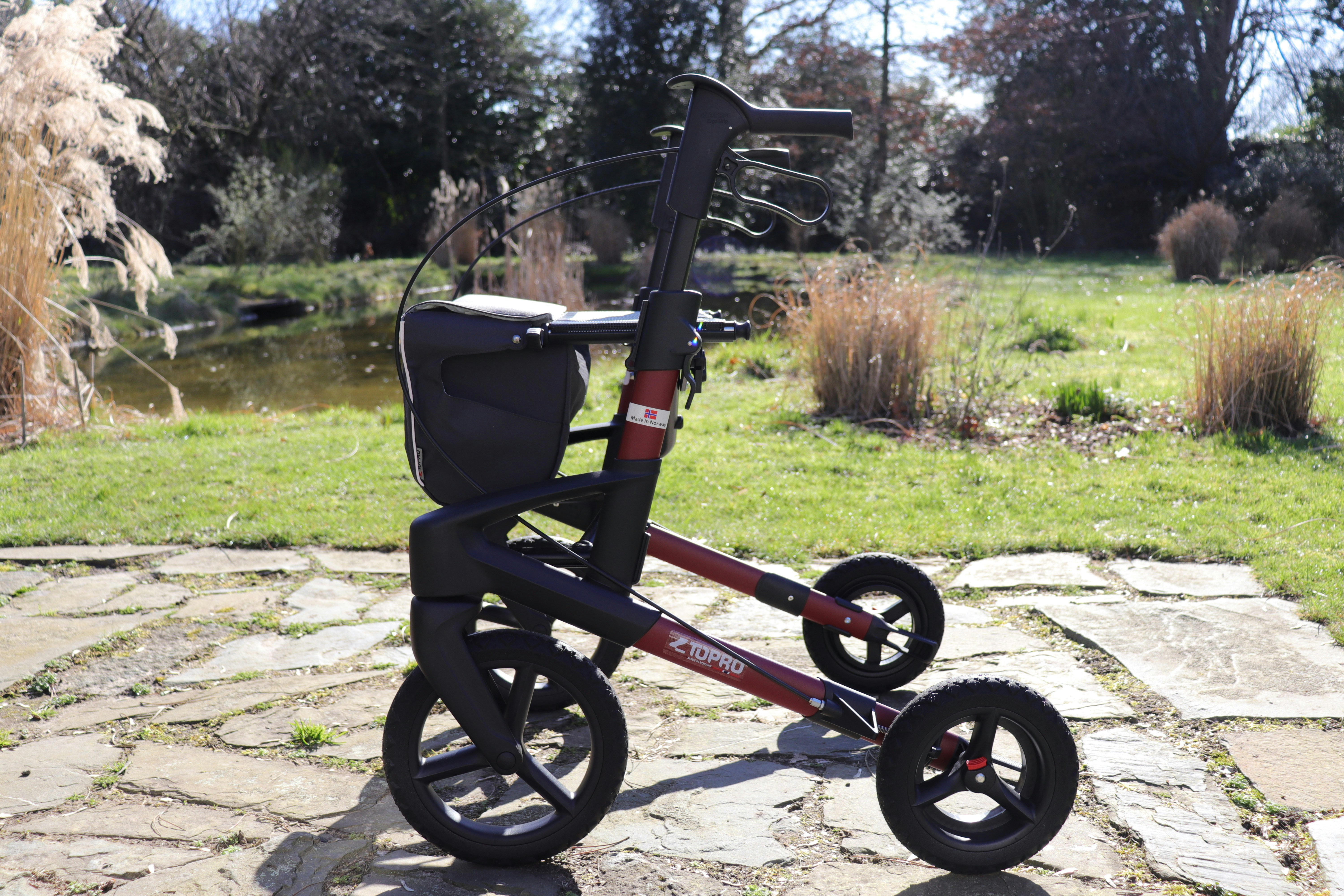 A red and black walker with a seat and basket.