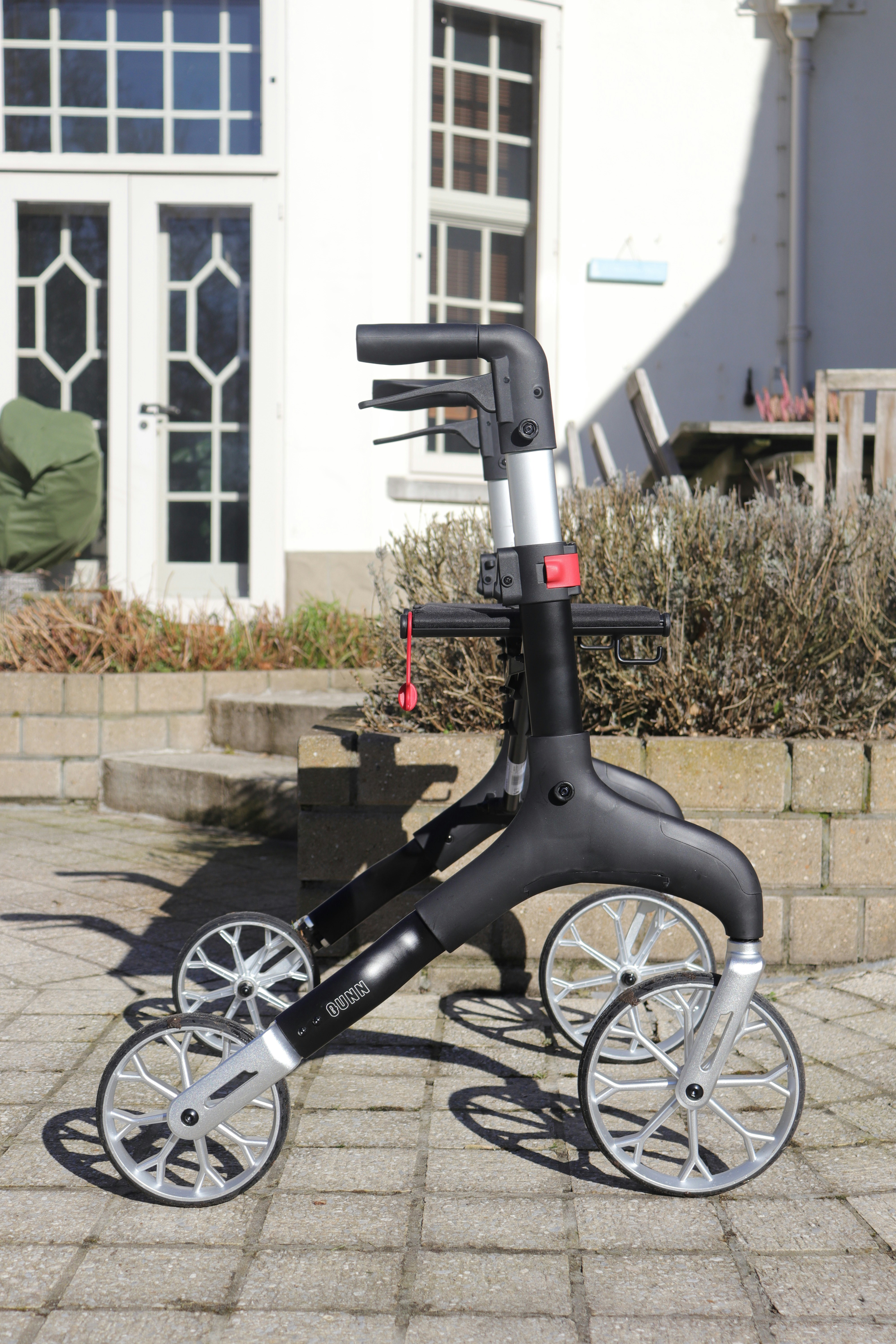 A black and silver walker with four wheels.