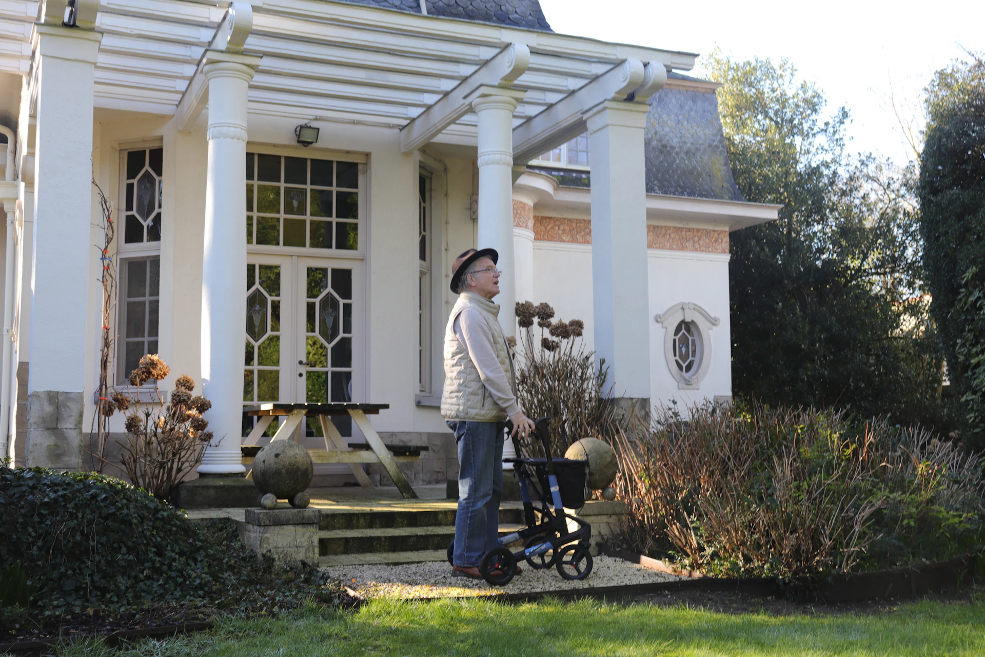 Elderly person with walker in front of a house