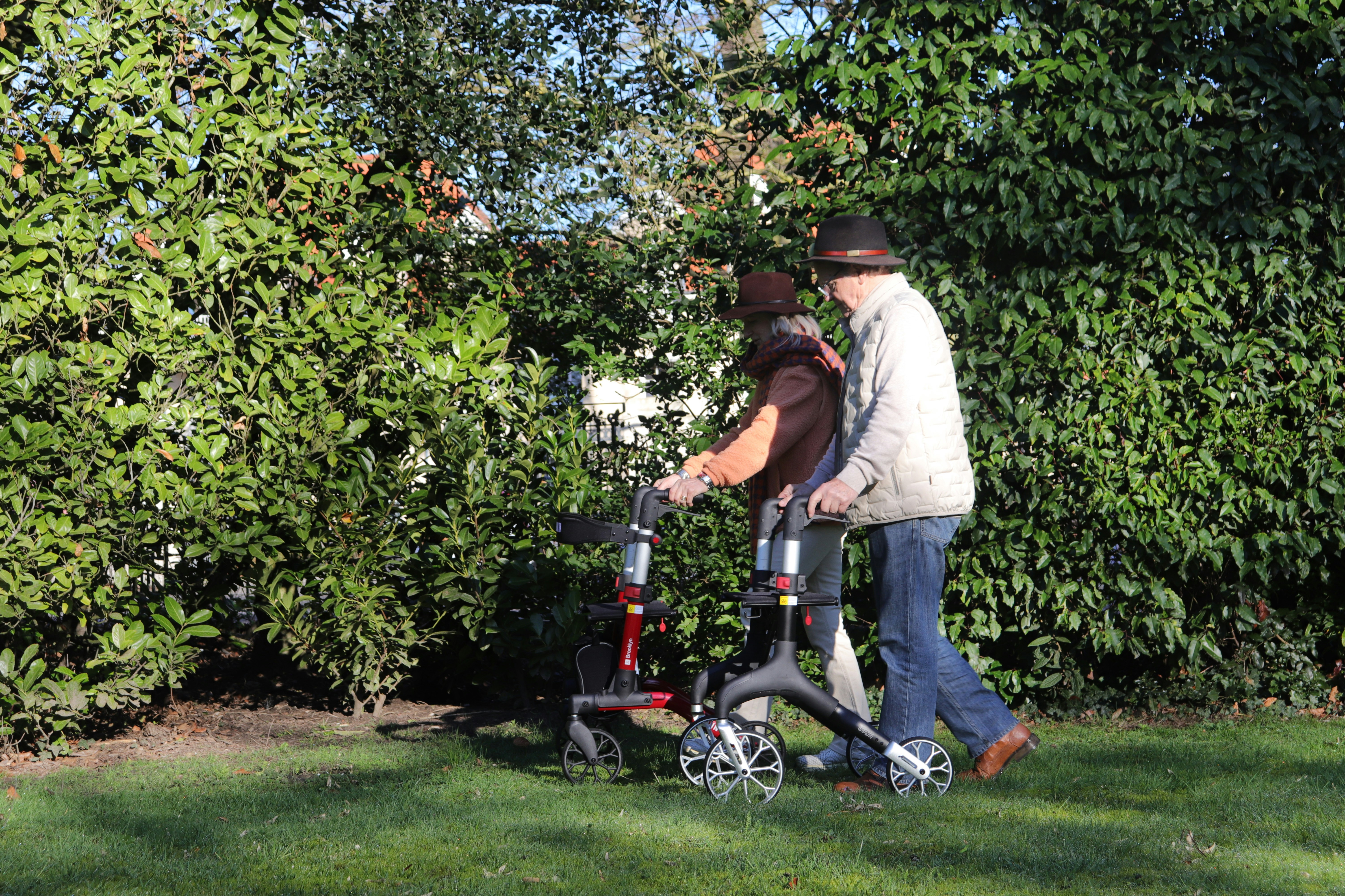 Man helps woman with walker in garden.