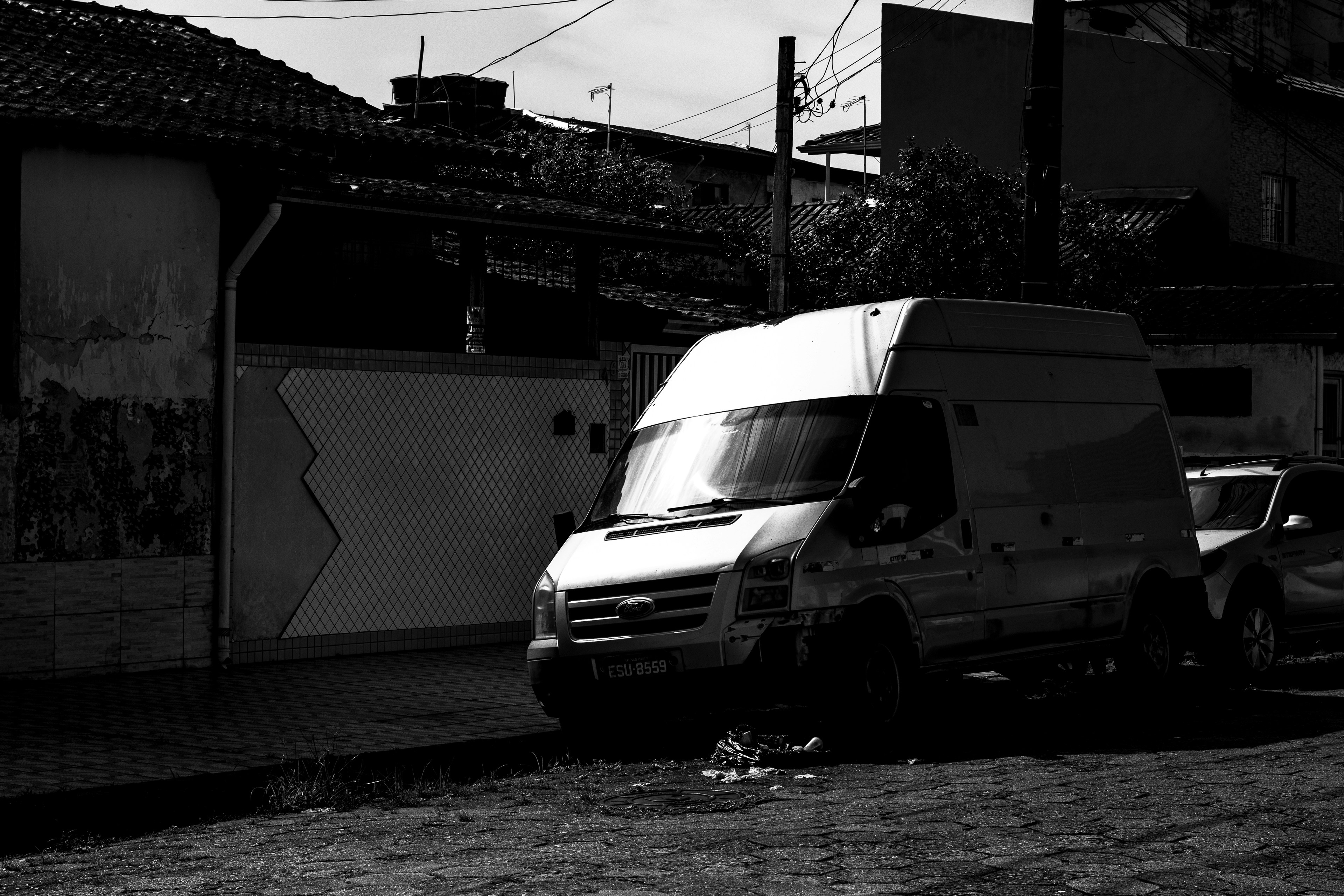 White van parked on a street next to buildings.
